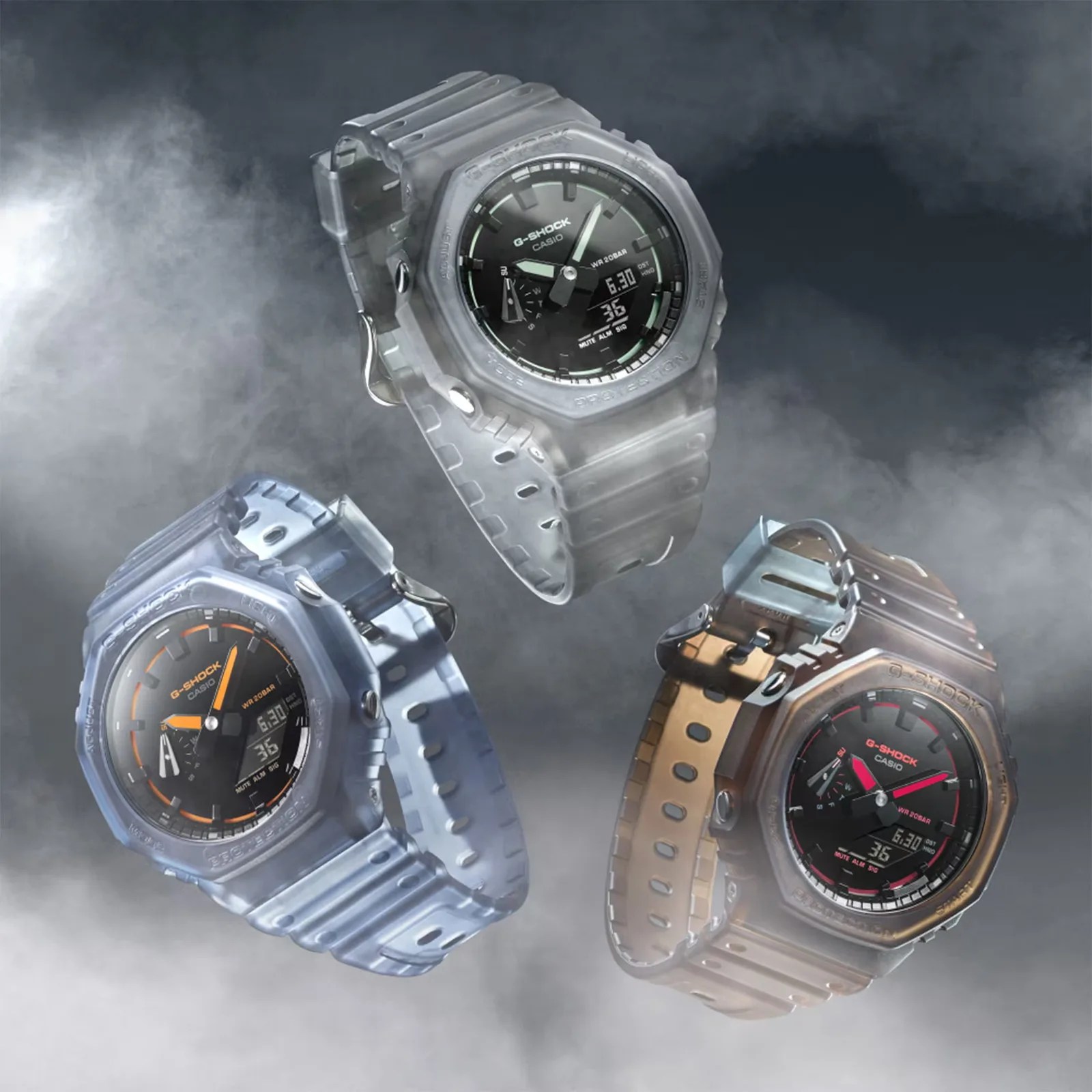 Three translucent G-Shock Casio watches with black faces and colored accents (green, orange, red) floating against a smoky dark background.