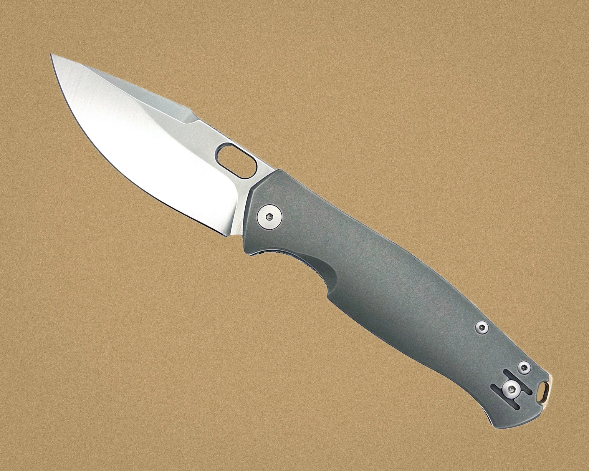 Folding knife with a silver blade and gray handle on a tan background.