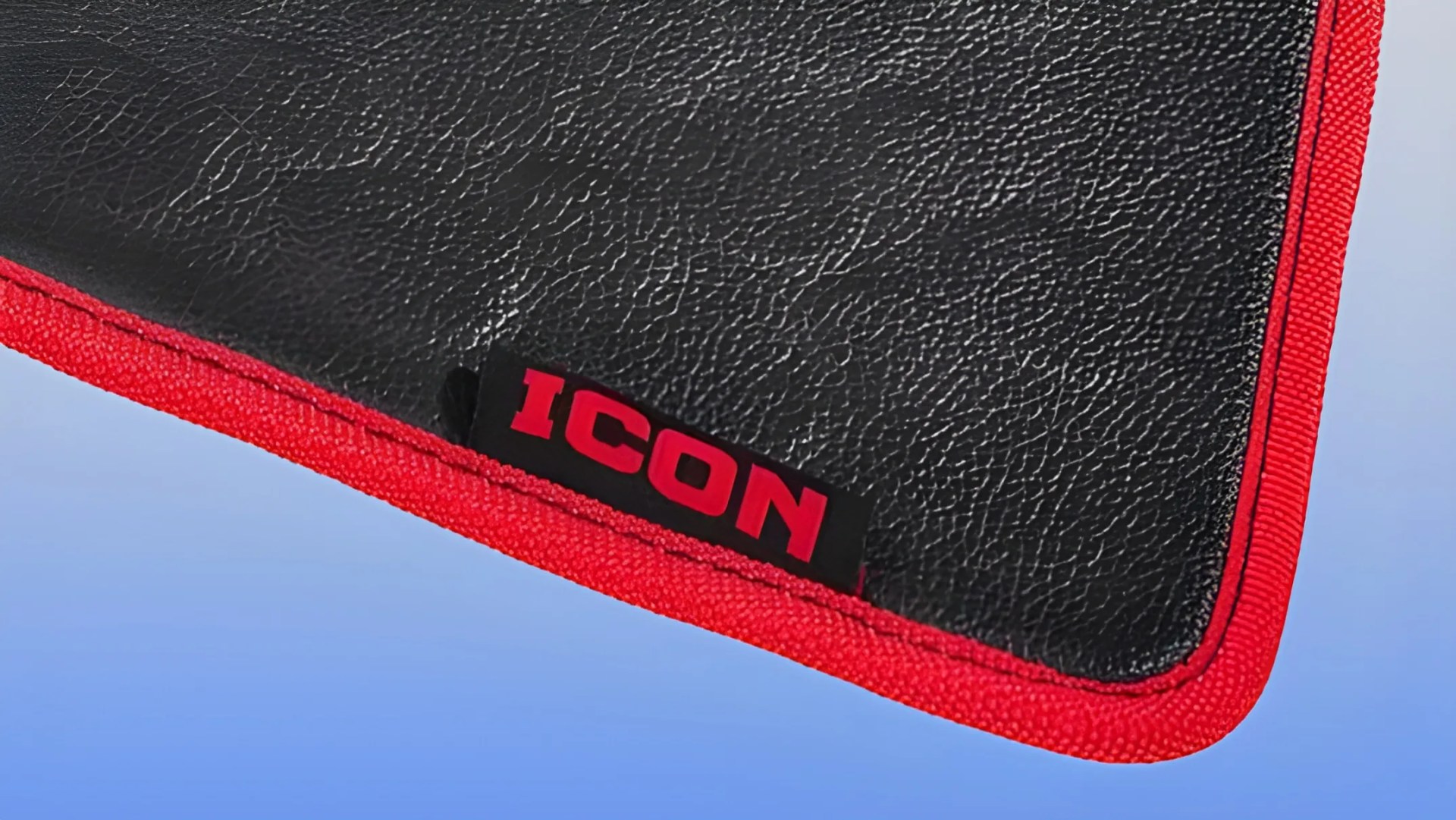 Black textured mat with red fabric trim and a black tag with red "ICON" text on a blue background.