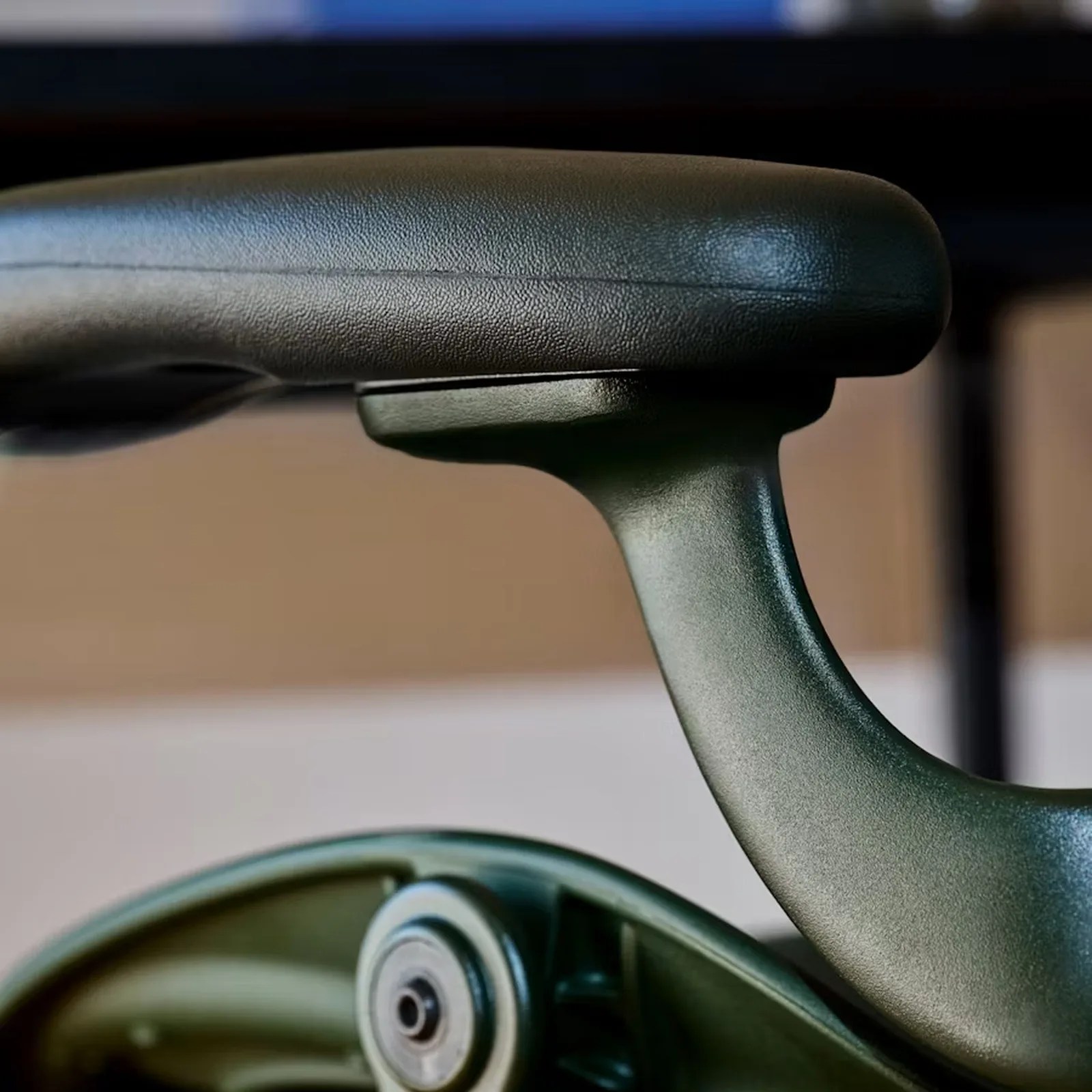 Close-up of a black textured armrest and green plastic support of an office chair.