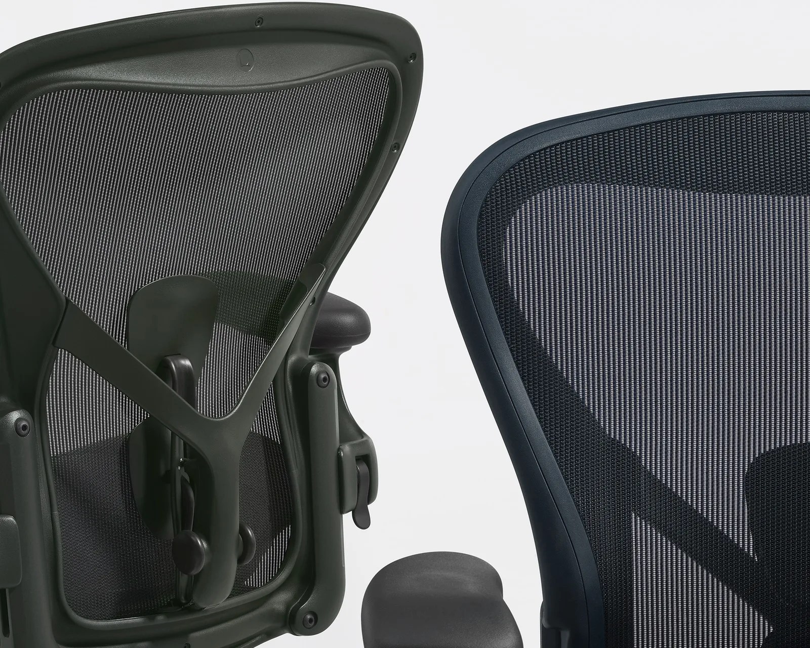 Close-up of two ergonomic office chair backs with black mesh and adjustable lumbar support.