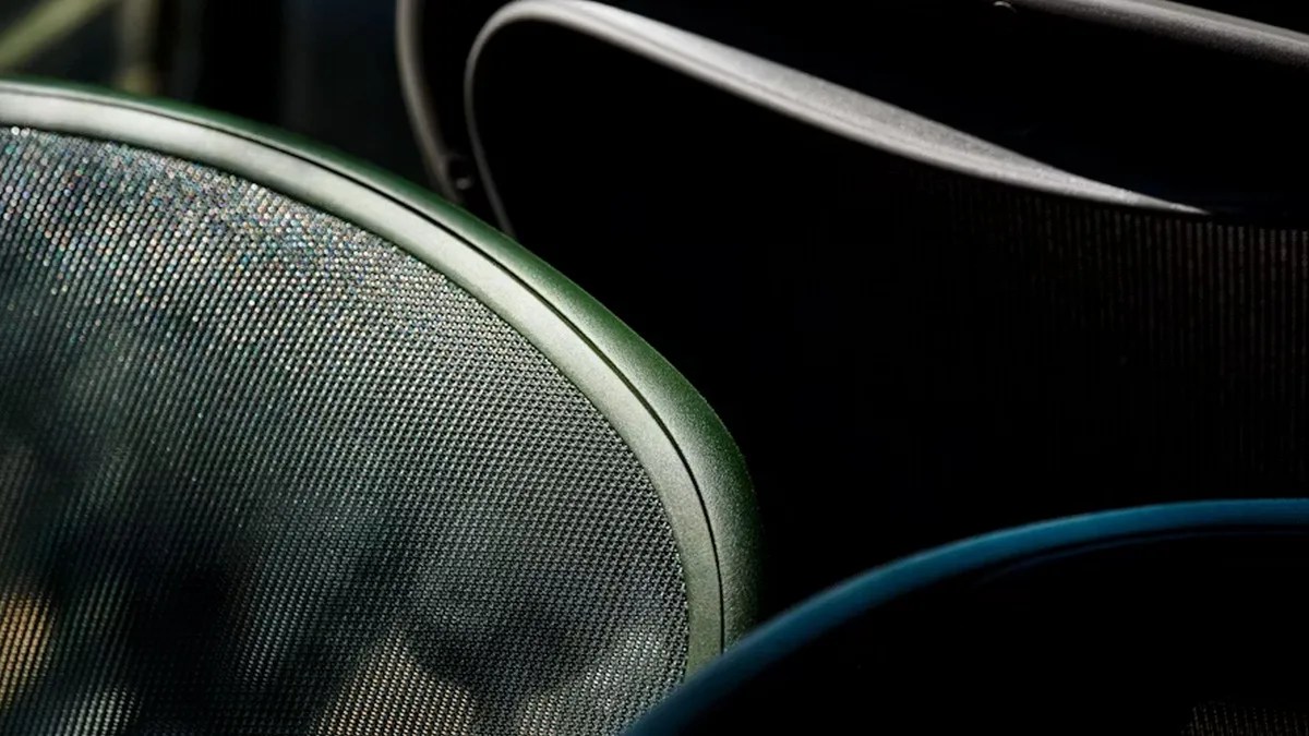 Close-up of dark green and black mesh chair backs with curved frames in shadowed lighting.