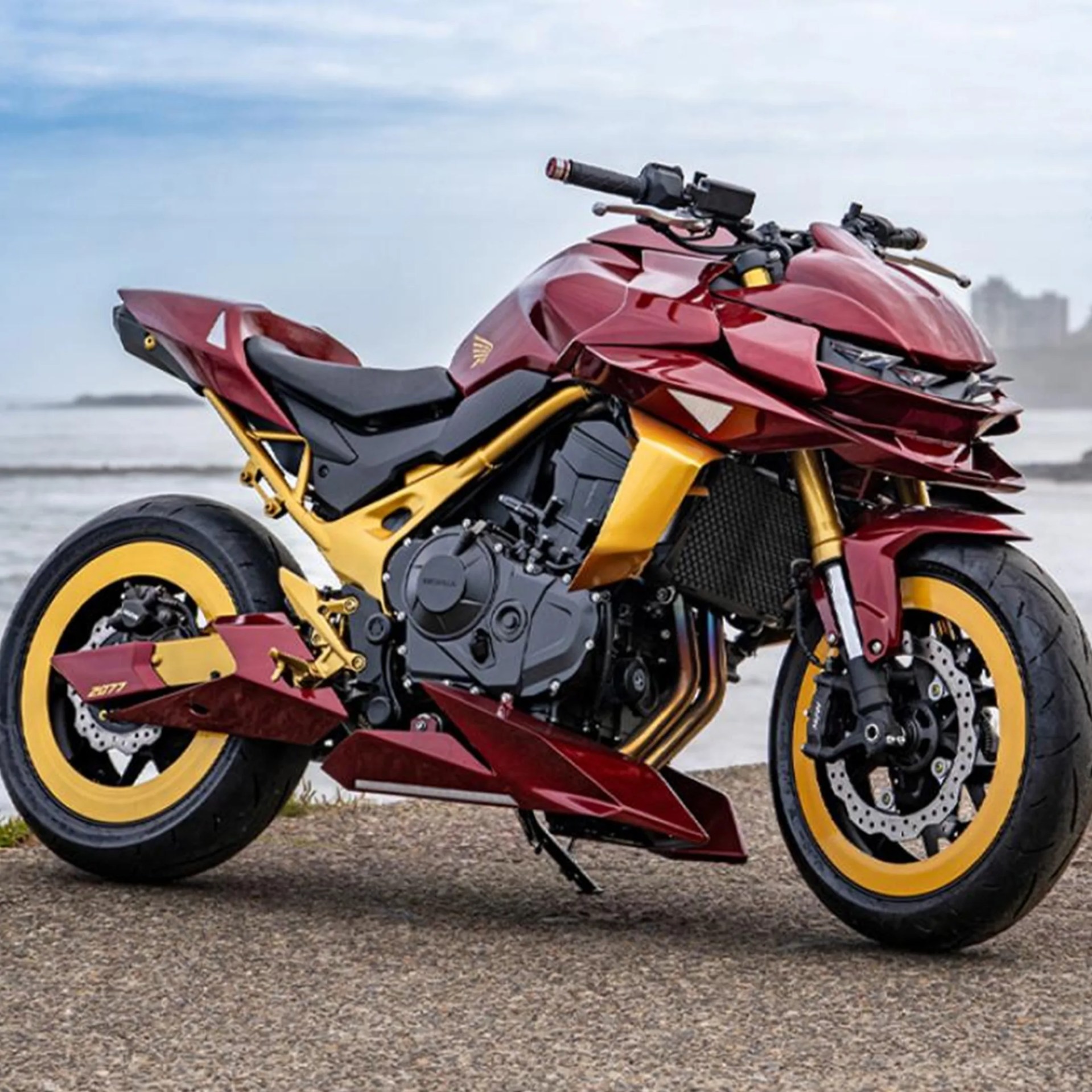 Red and gold sport motorcycle with black engine and yellow-rimmed tires parked on a gravel surface.