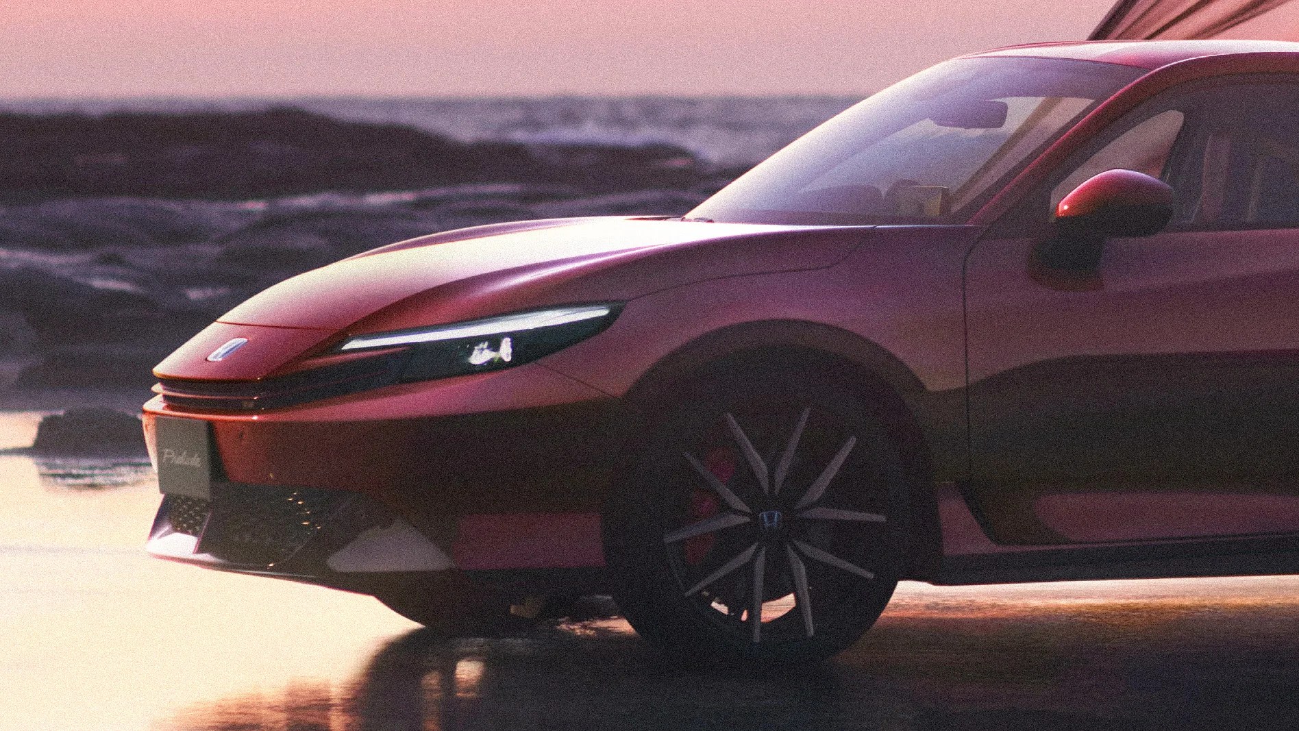 Front side view of a red car with sleek headlights and black alloy wheels parked near rocky terrain at sunset.