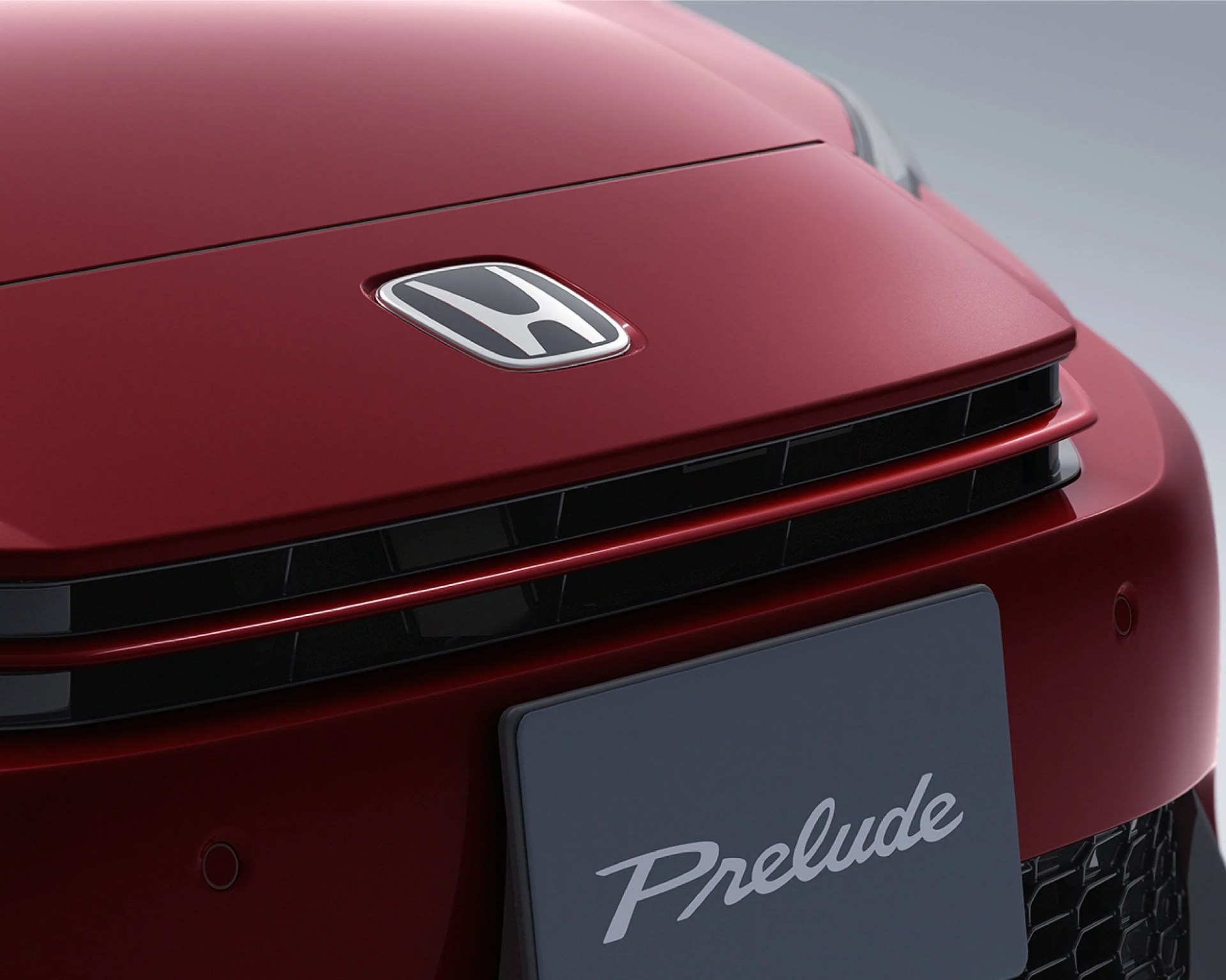 Close-up of a red Honda car hood with the Honda logo and a front license plate reading "Prelude.