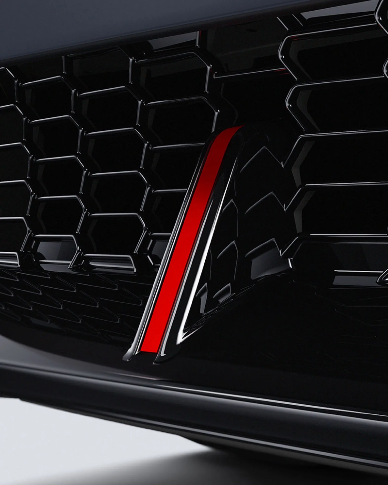Glossy black honeycomb car grille with a vertical red accent stripe.