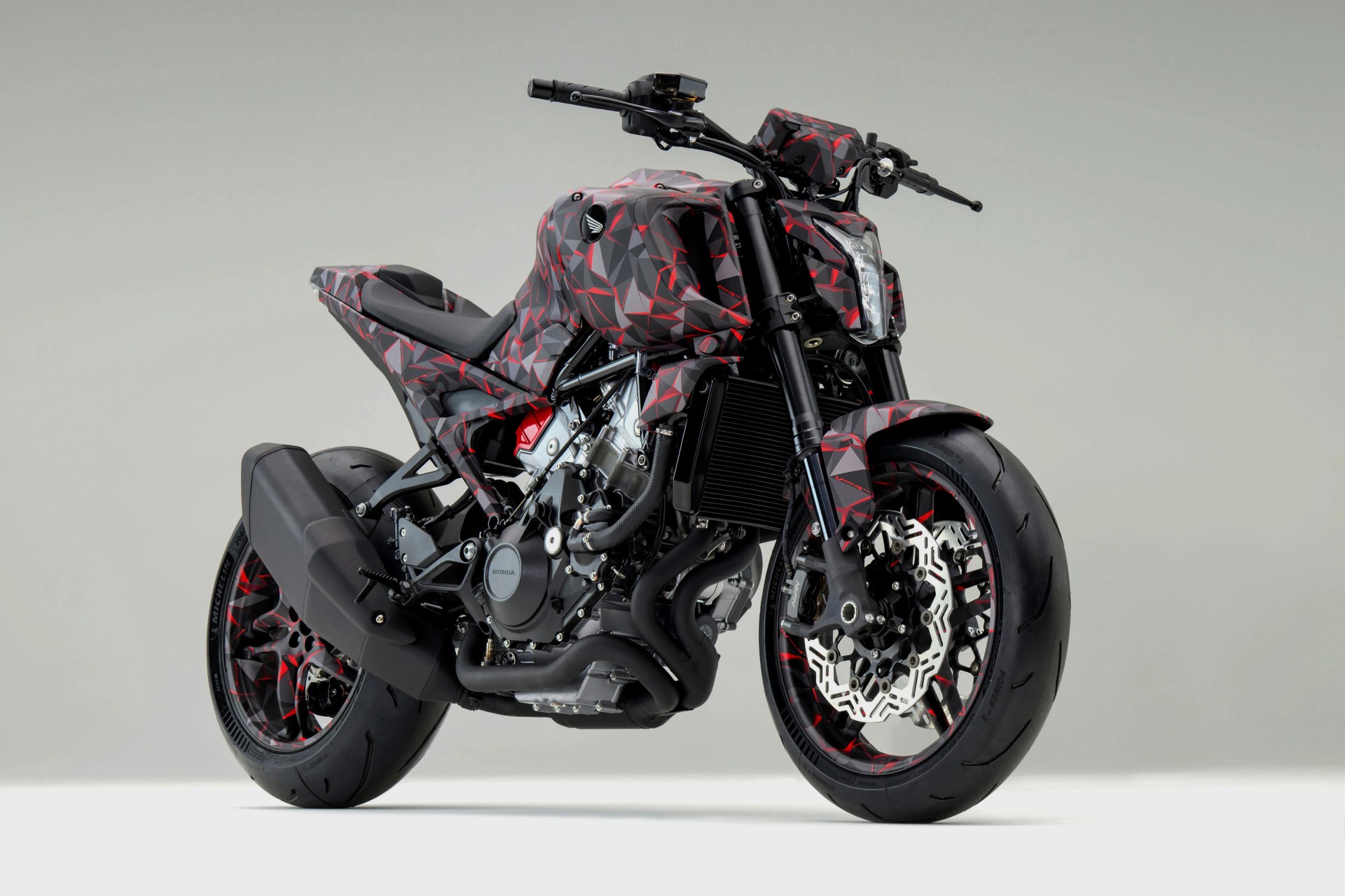 Sport motorcycle with a black and red geometric camouflage pattern and exposed engine components.