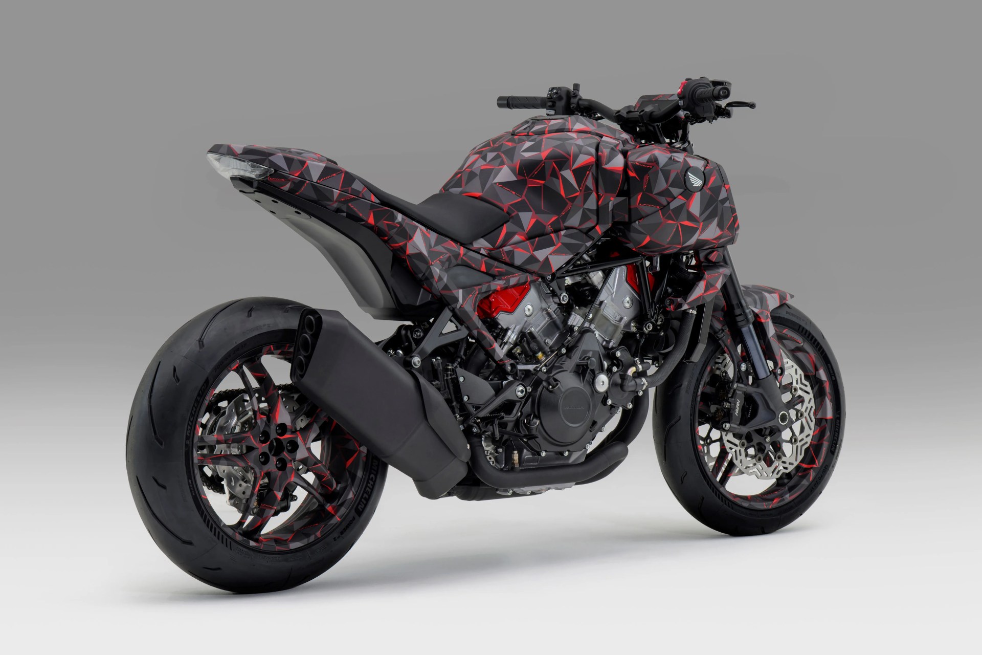 Sport motorcycle with a black, red, and gray geometric patterned body and black exhaust system.