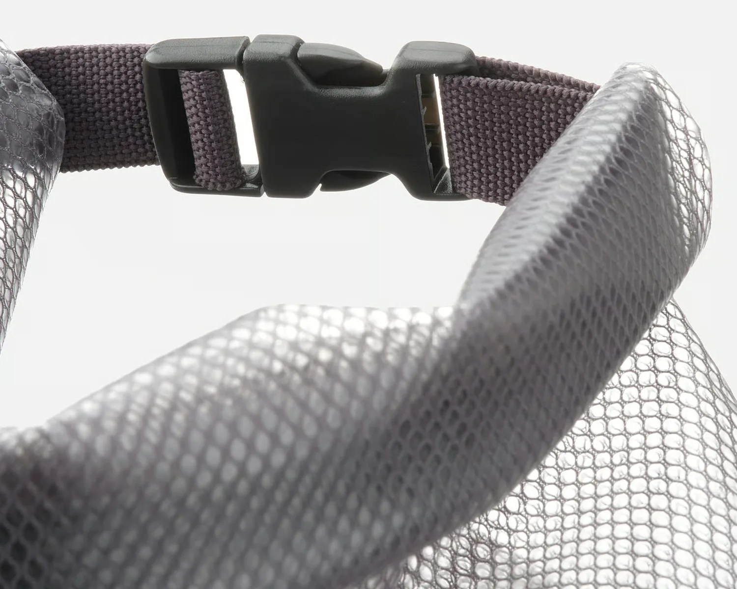 Close-up of a black plastic buckle attached to a dark gray woven strap and a silver mesh fabric.