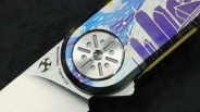 Close-up of a folding knife pivot with a colorful handle featuring a cityscape design and blade marked "K214B51 CPM S35VN.