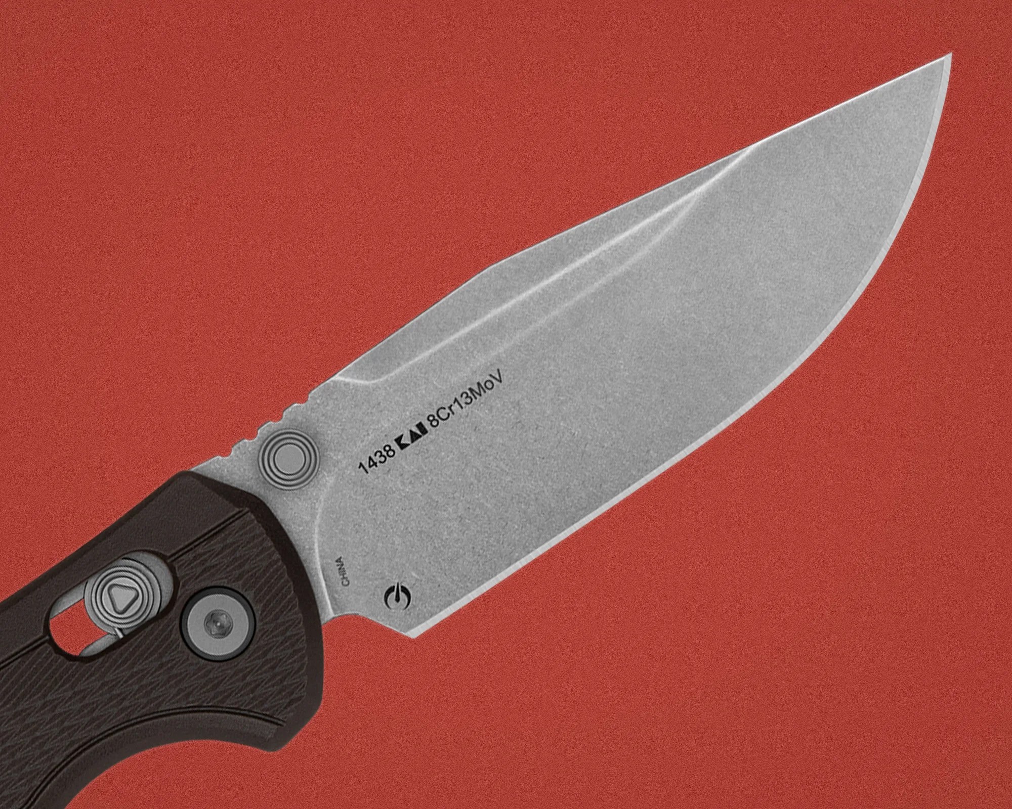 Knife blade with stonewashed finish and black textured handle on a red background.
