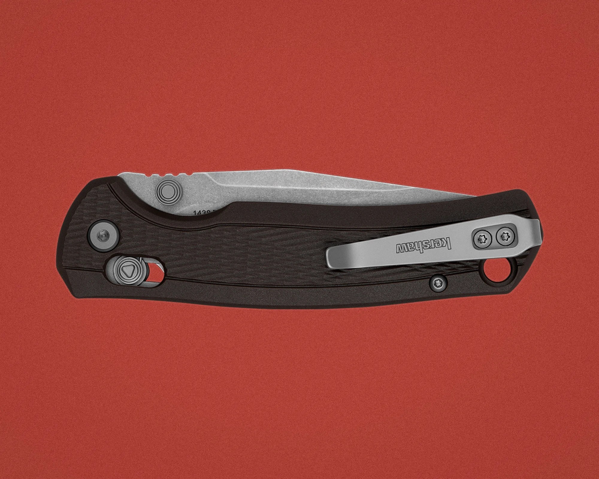 Black folding pocket knife with a partially visible stonewashed blade and silver clip on a red background.