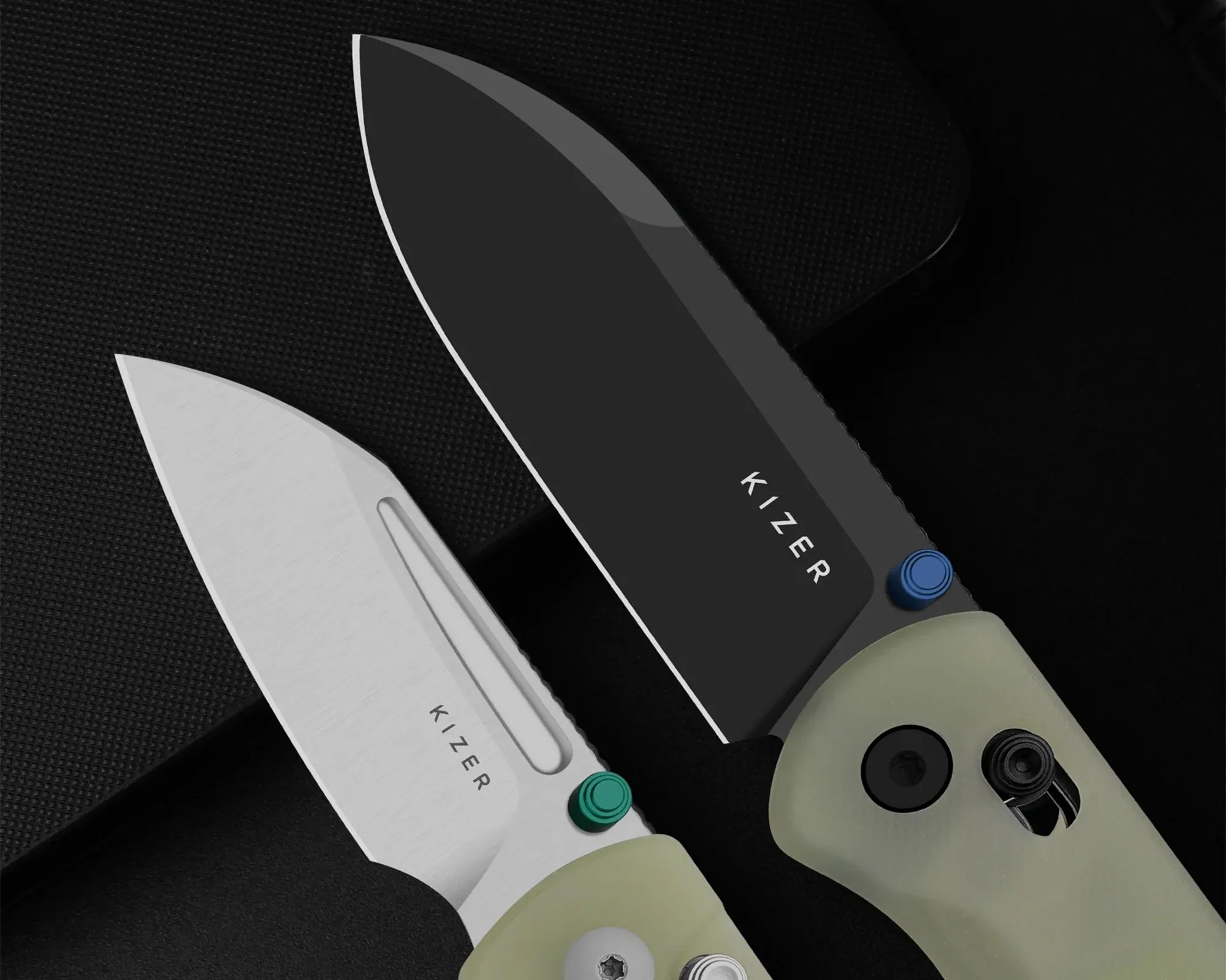 Two Kizer brand folding knives with one blade black and the other silver, both with light-colored handles.