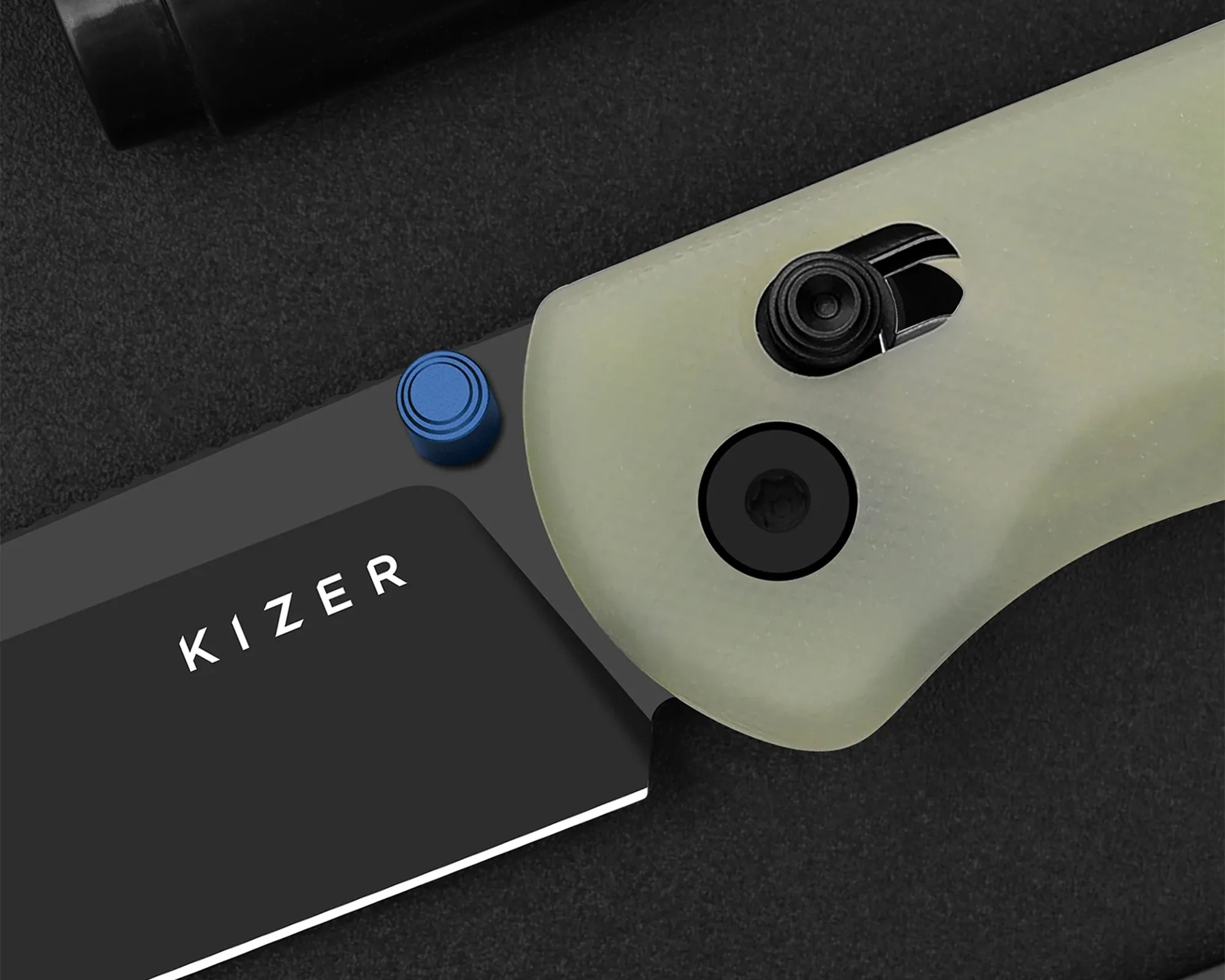 Close-up of a knife handle with a translucent green grip, black screws, a blue pivot collar, and part of a black blade with "KIZER" text.