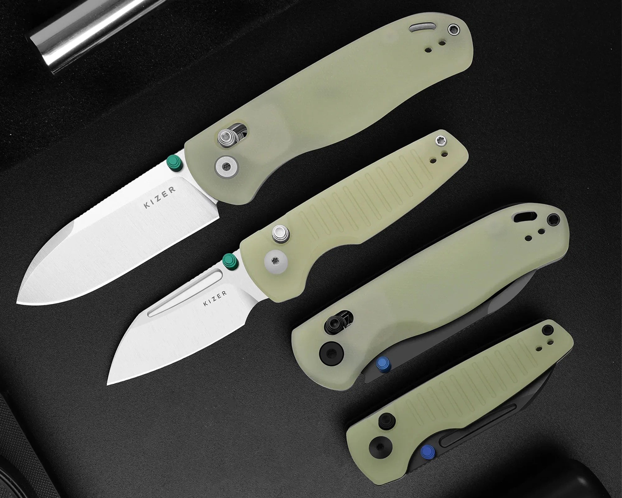 Four folding knives with light green handles and silver blades, two blades partially open, on a black surface.