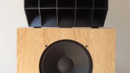 Large wooden speaker cabinet with a black circular speaker and a black horn-loaded tweeter on top.