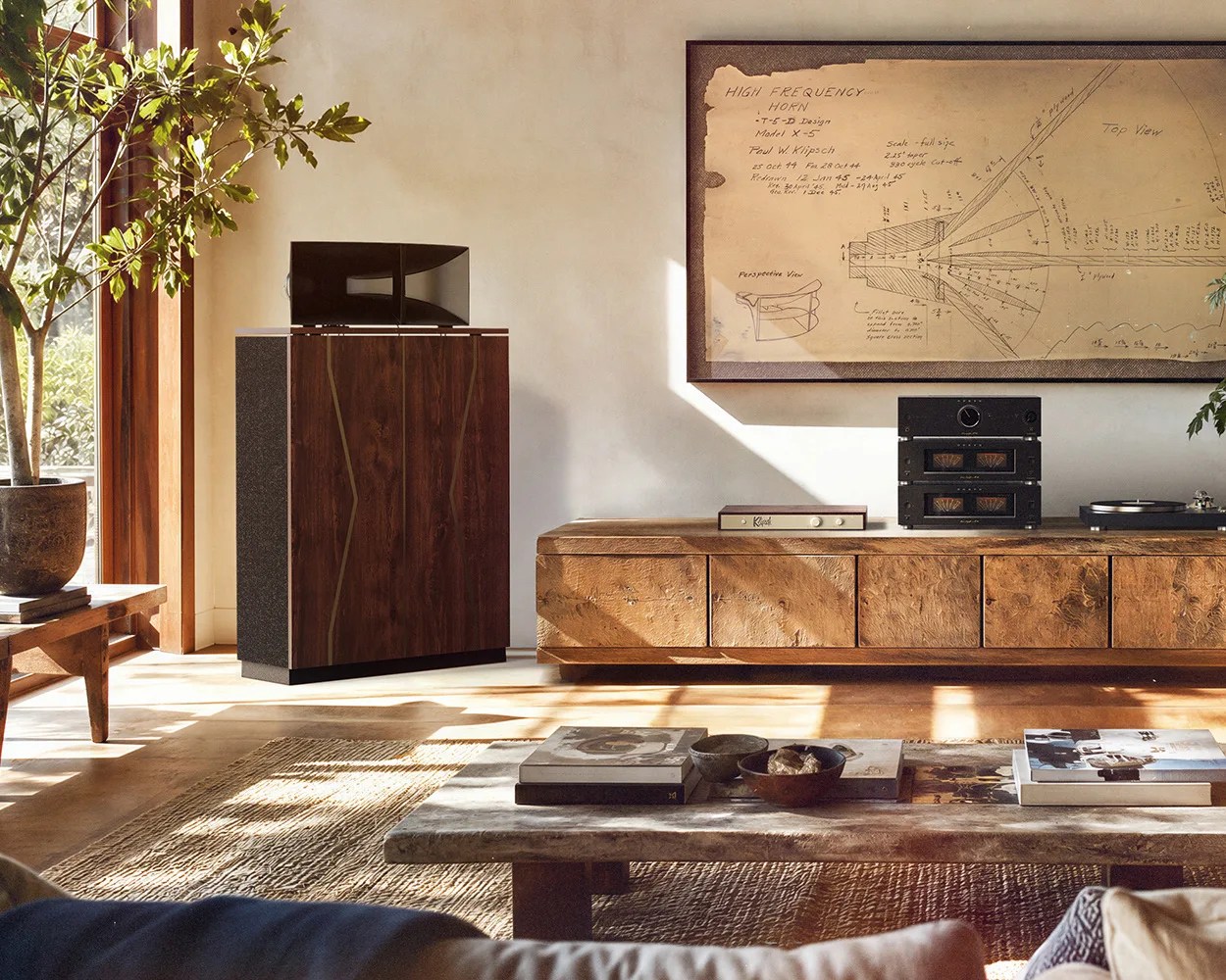 Large vintage wooden speaker with a black horn on top in a sunlit living room corner.