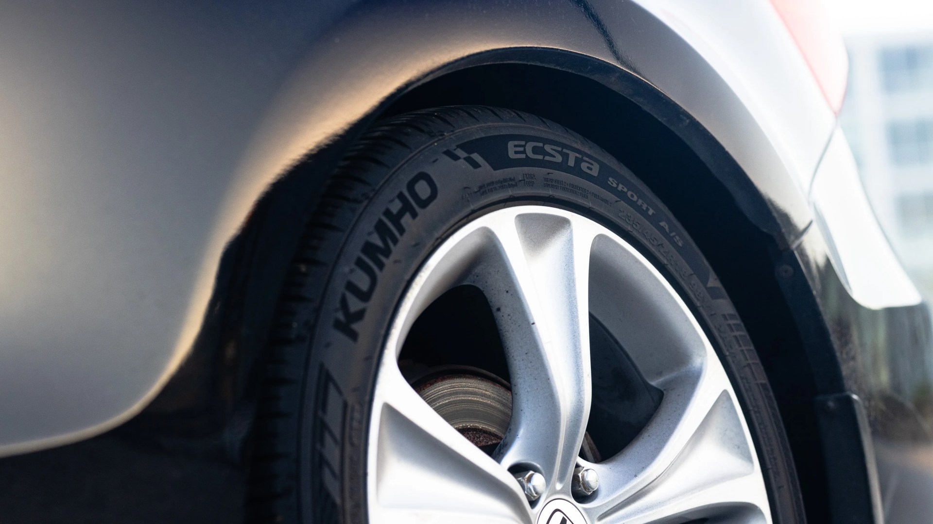 Close-up of a Kumho Ecsta Sport A/S tire mounted on a silver alloy wheel of a vehicle.