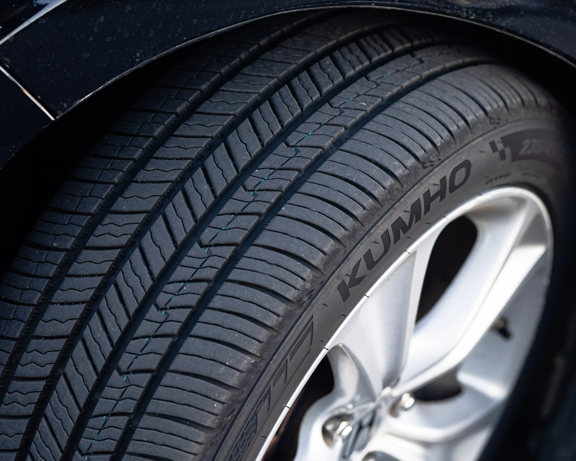 Close-up of a black Kumho tire with detailed tread pattern mounted on a silver alloy wheel.