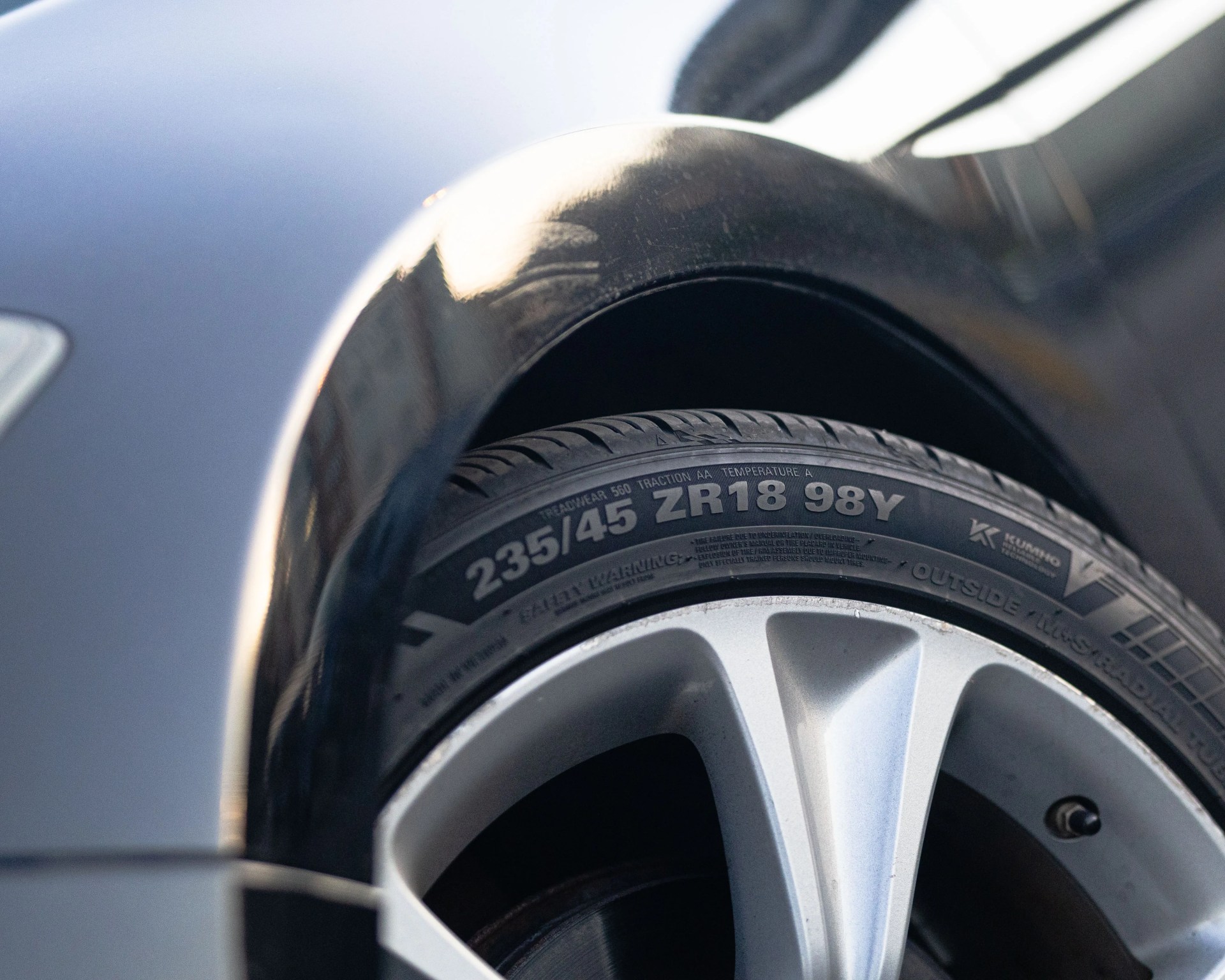 Close-up of a car tire with visible tread pattern and silver alloy wheel rim.