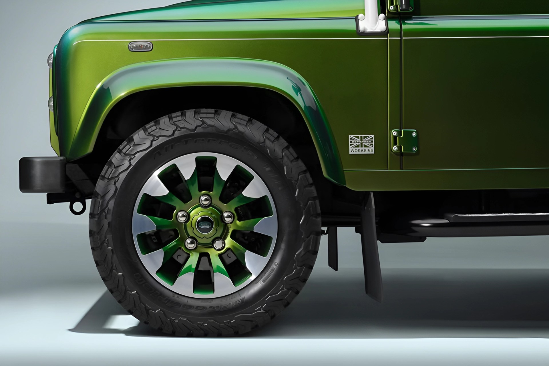 Close-up of a green metallic off-road vehicle's front wheel and fender with a "Works V8" badge.