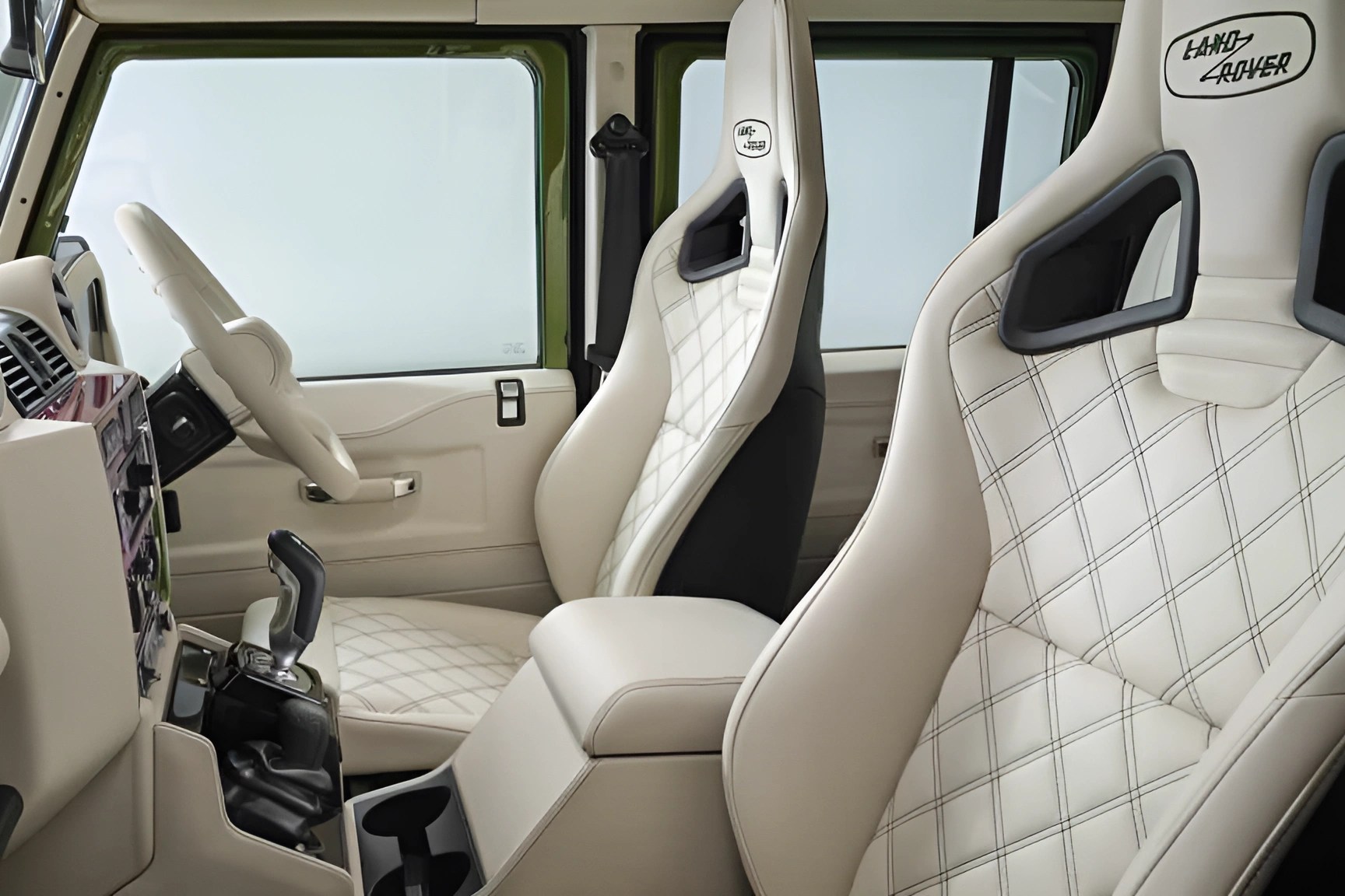 Cream leather Land Rover car seats with diamond stitching and black accents inside a vehicle.