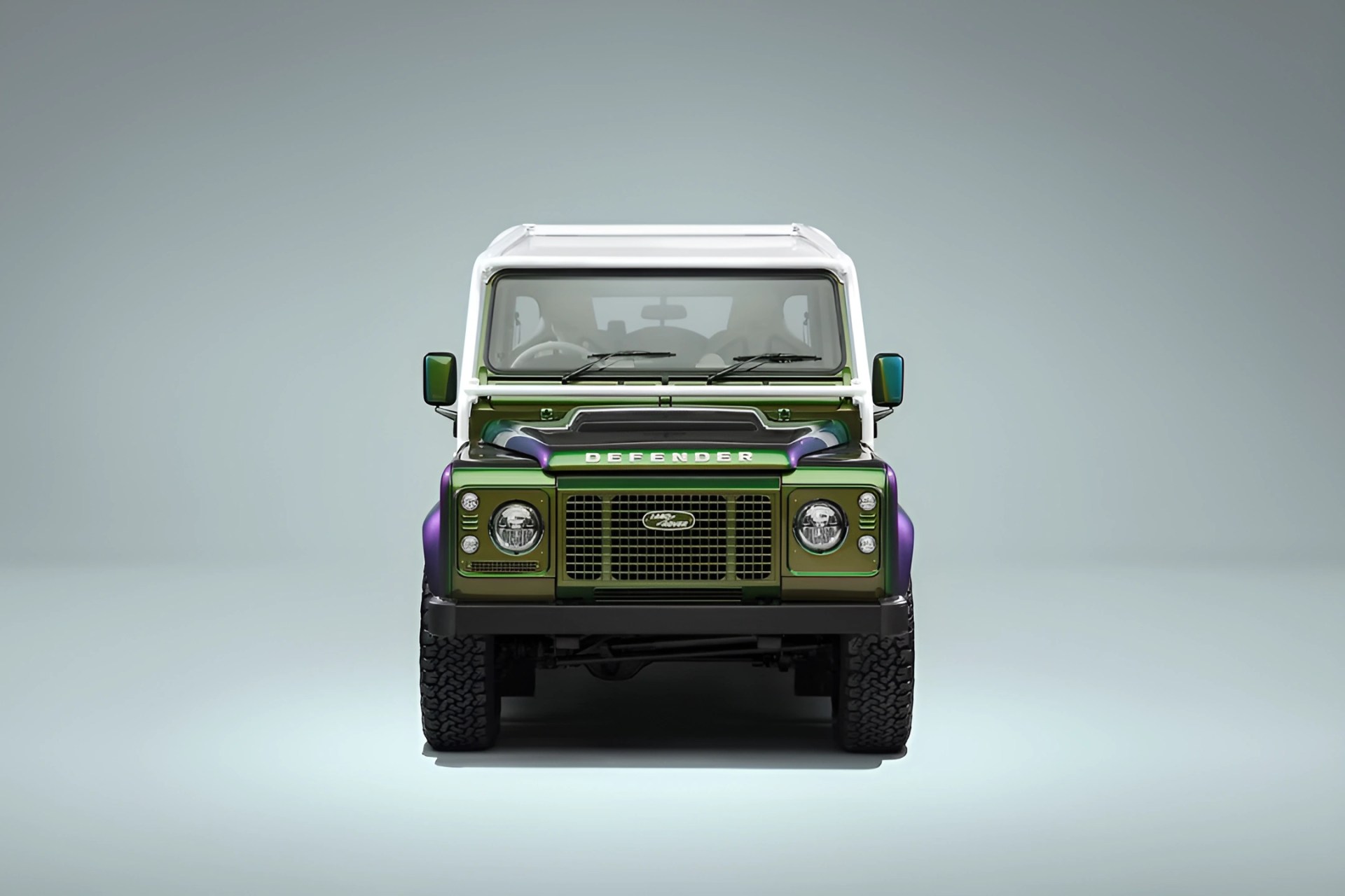 Front view of a green and purple Land Rover Defender with a white roof against a plain background.