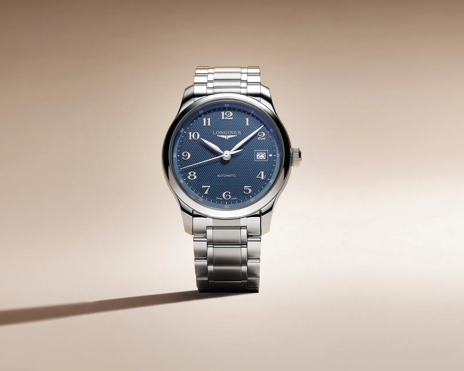 Silver metal wristwatch with a textured blue dial, Arabic numerals, and date window at 3 o'clock.