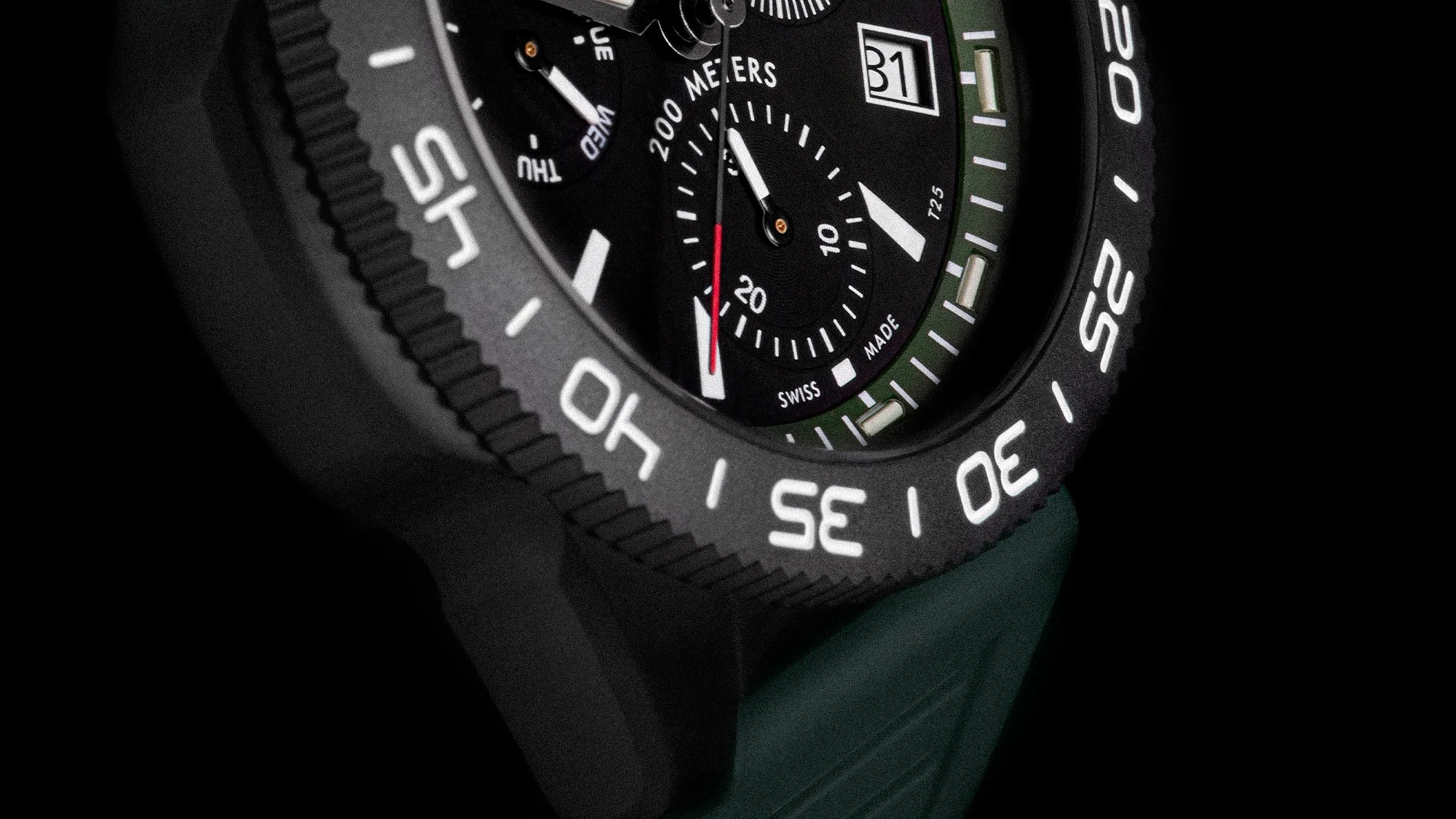Close-up of a black dive watch face with white markings, a date window showing 31, and a green strap.