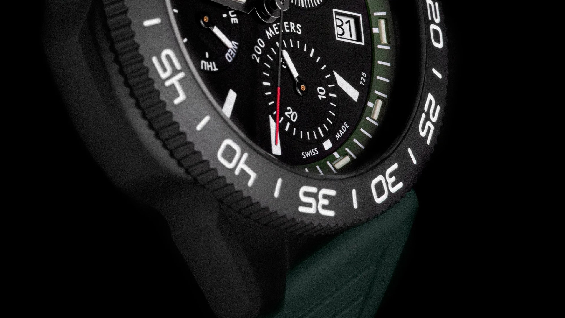 Close-up of a black dive watch face with white markings, a date window showing 31, and a green strap.