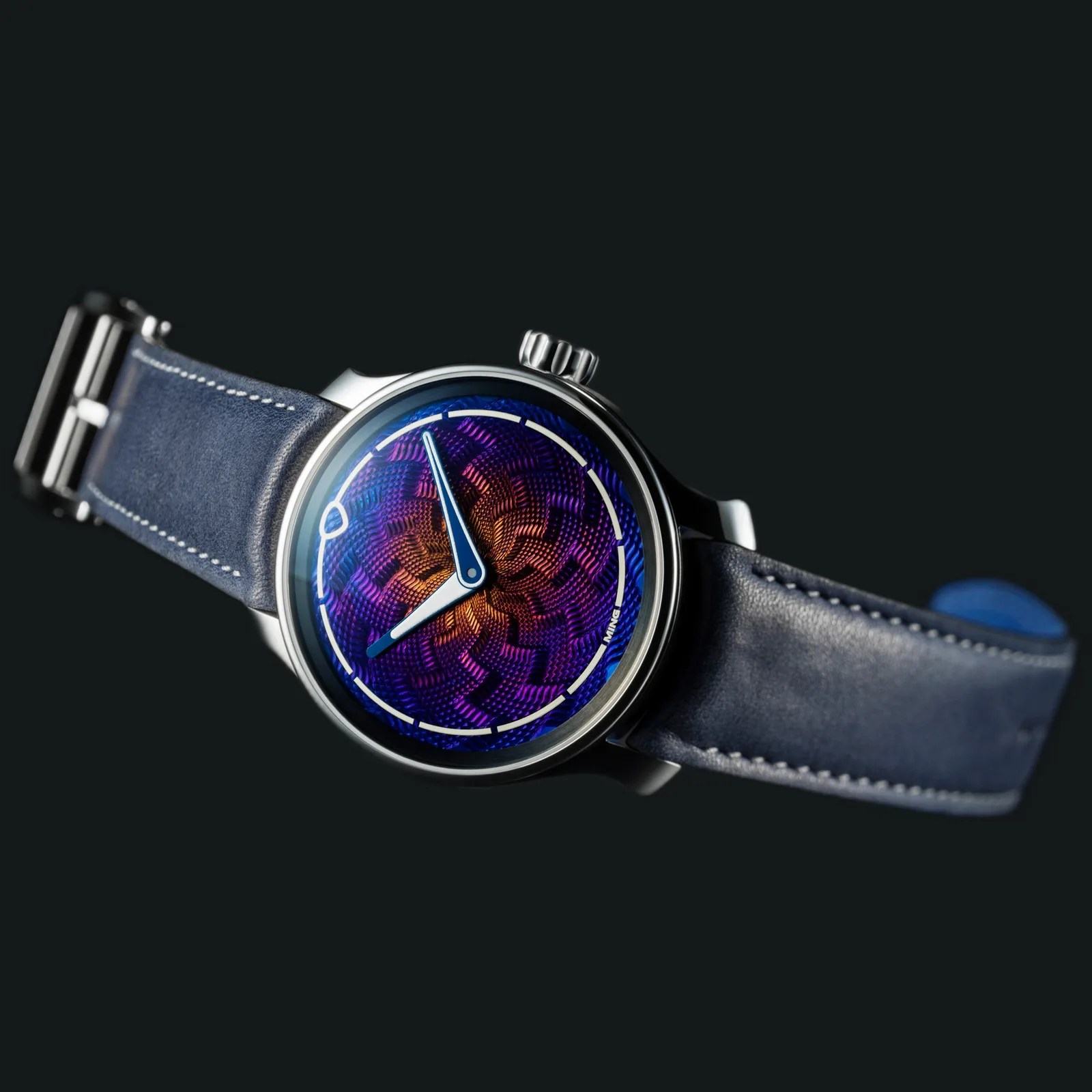 Round wristwatch with a vibrant purple and orange textured dial, blue leather strap, and silver case.
