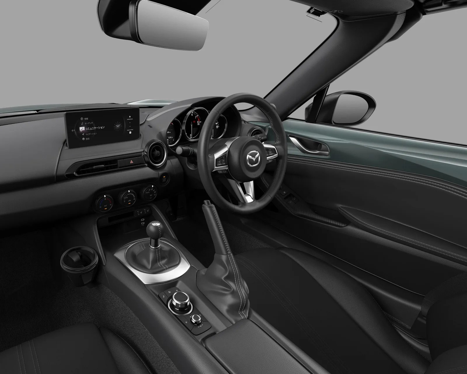 Black leather interior of a Mazda car with a manual gear shift and digital display screen.