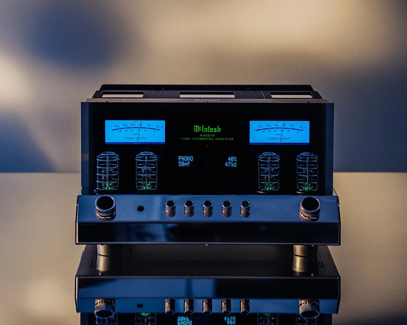 McIntosh MA2375 tube integrated amplifier with blue power output meters and metal control knobs on a reflective surface.