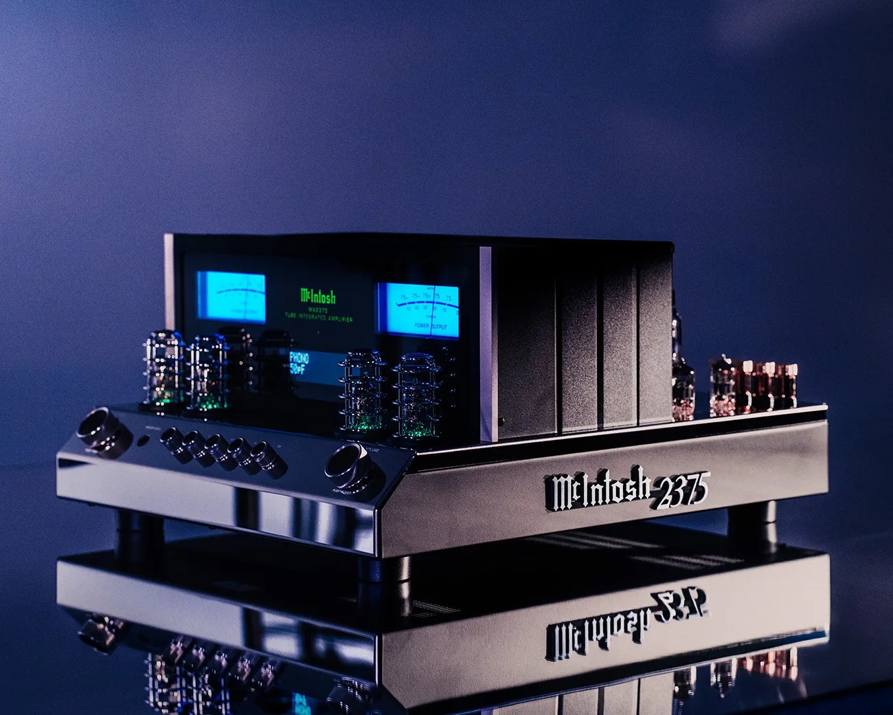 McIntosh 2375 tube integrated amplifier with blue-lit meters and chrome knobs on a reflective surface.