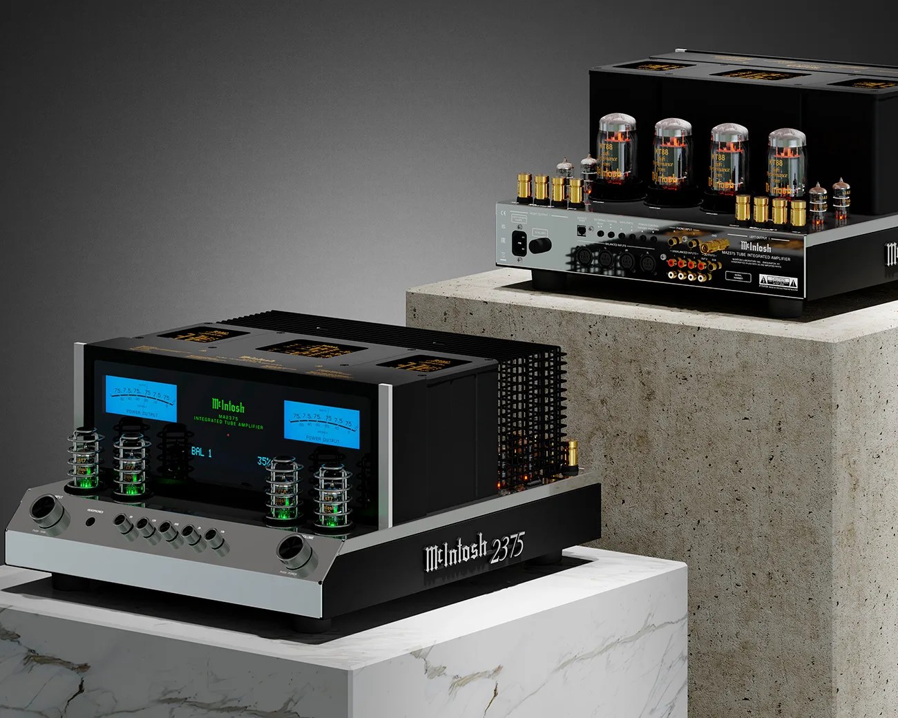 Two McIntosh integrated tube amplifiers, one with blue power output meters and green-lit tubes on a marble pedestal, the other with exposed glowing tubes on a concrete pedestal.
