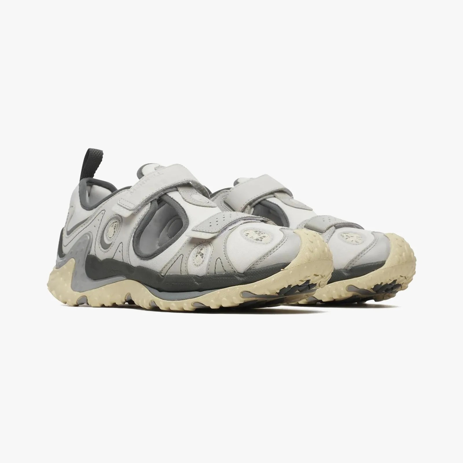Pair of light gray and beige athletic shoes with cutout sides and textured beige soles.