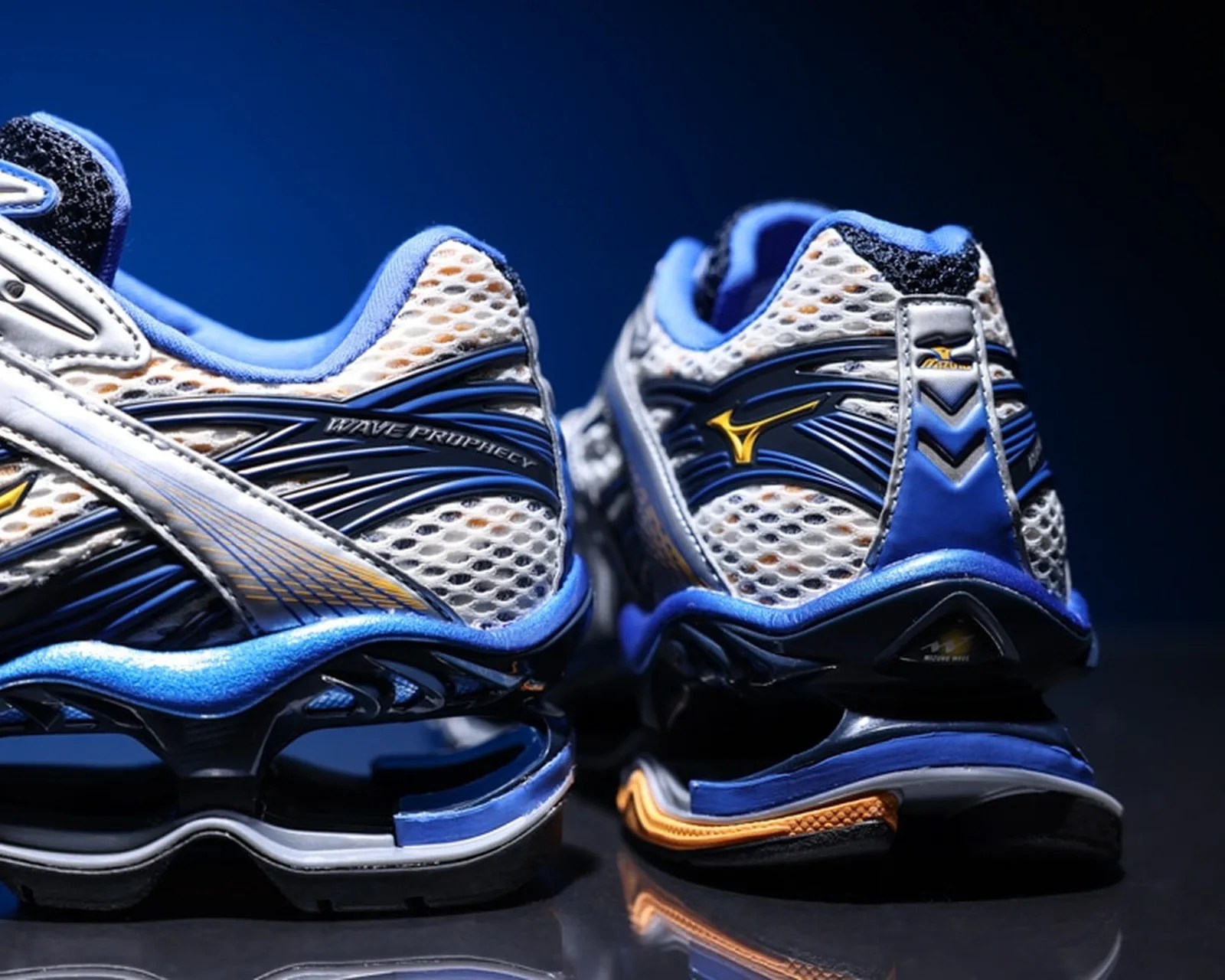 Pair of white and blue Mizuno Wave Prophecy running shoes with mesh uppers and visible sole springs.