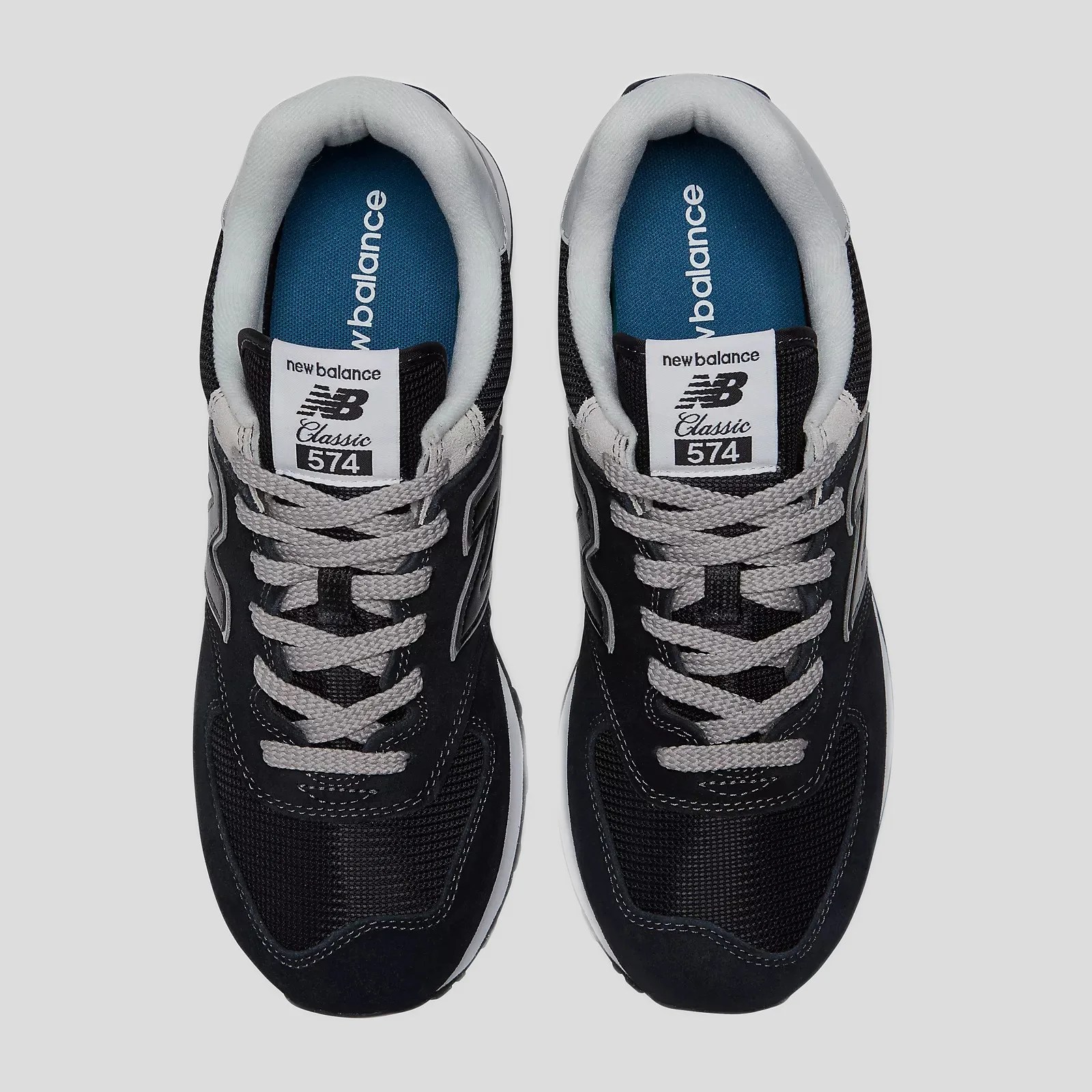 Pair of black New Balance Classic 574 sneakers with gray laces and blue insoles viewed from above.