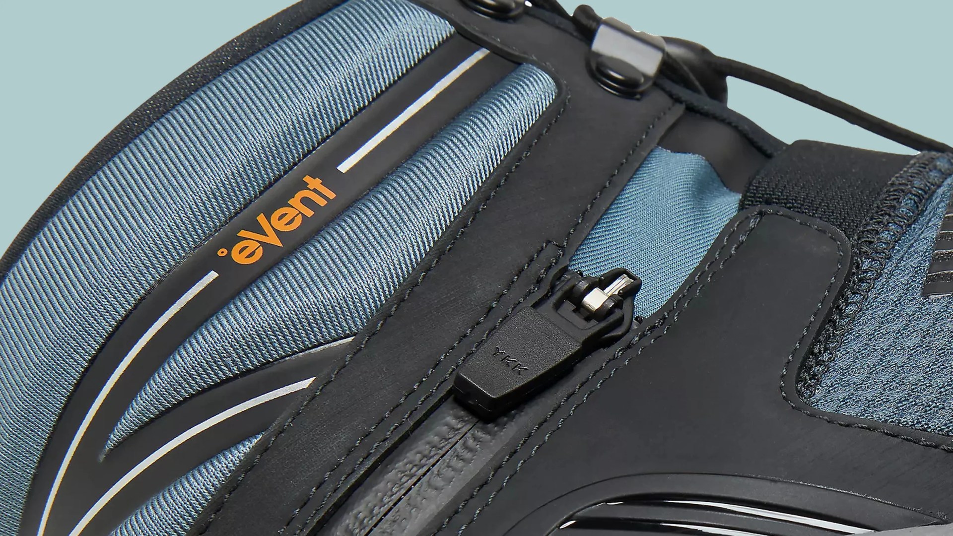 Close-up of a black and blue fabric item with a YKK zipper and orange "eVent" branding.