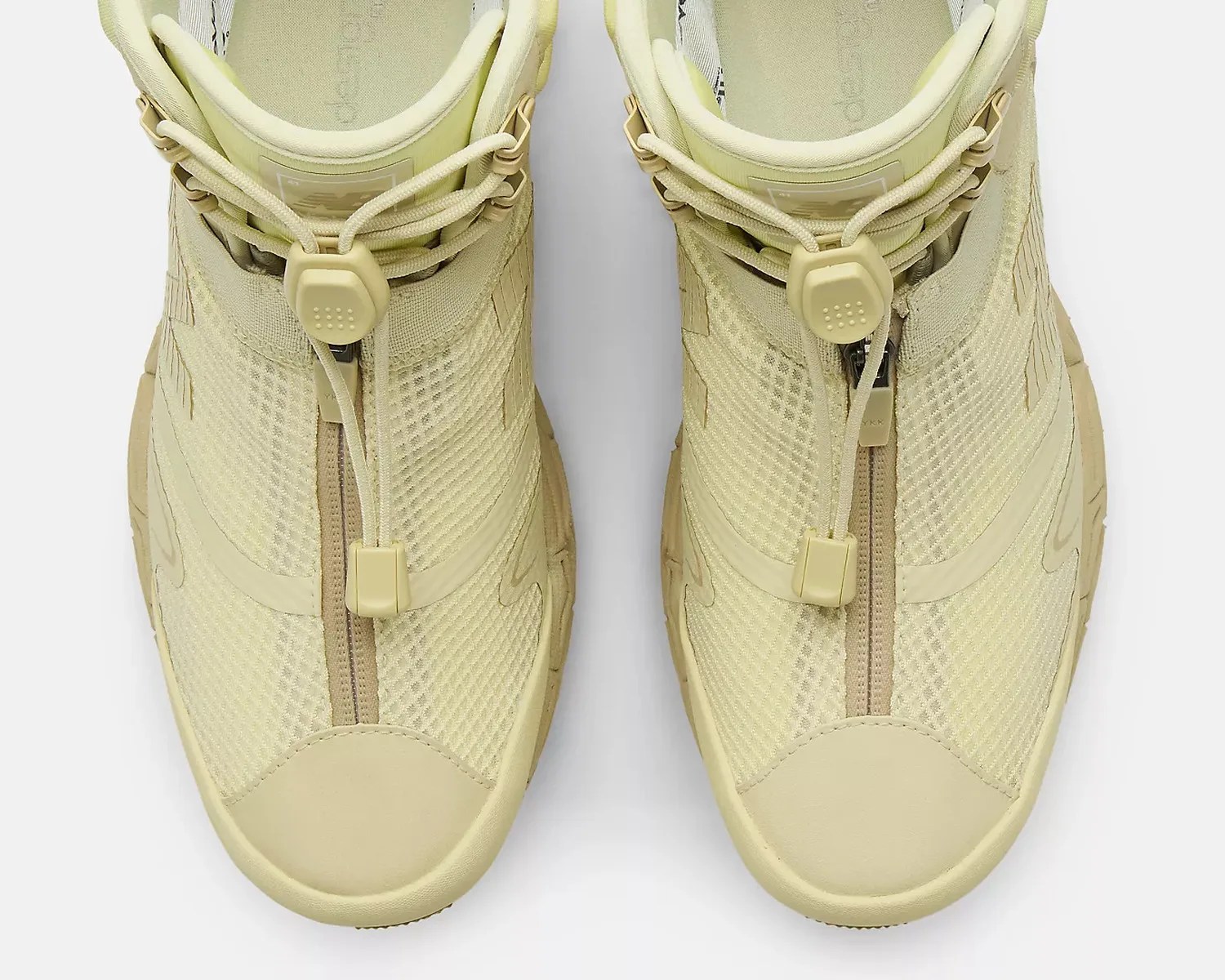Pair of beige mesh sneakers with front zipper and toggle lace closure, viewed from above.