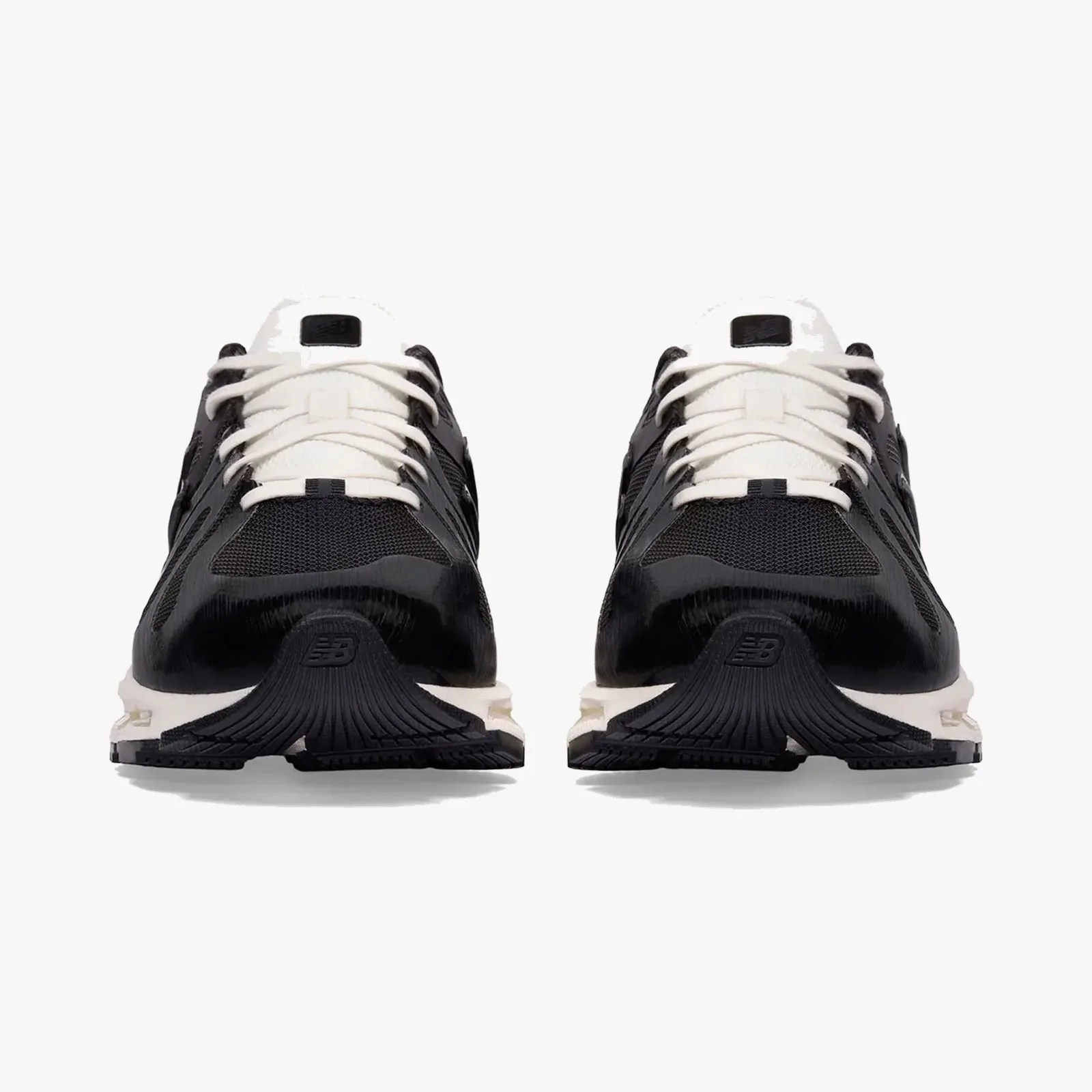 Pair of black and white New Balance sneakers viewed from the front with white laces and textured soles.