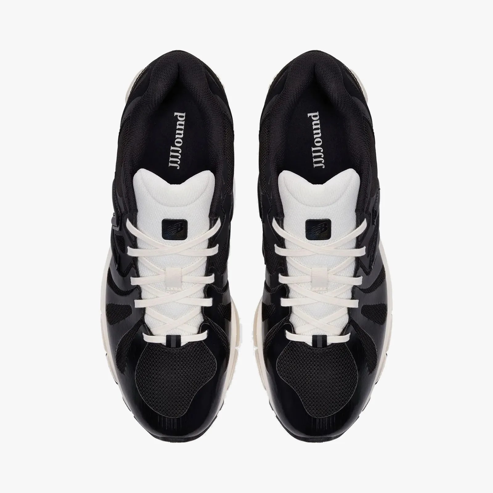 Pair of black and white New Balance sneakers with white laces and JJJJound branding inside.