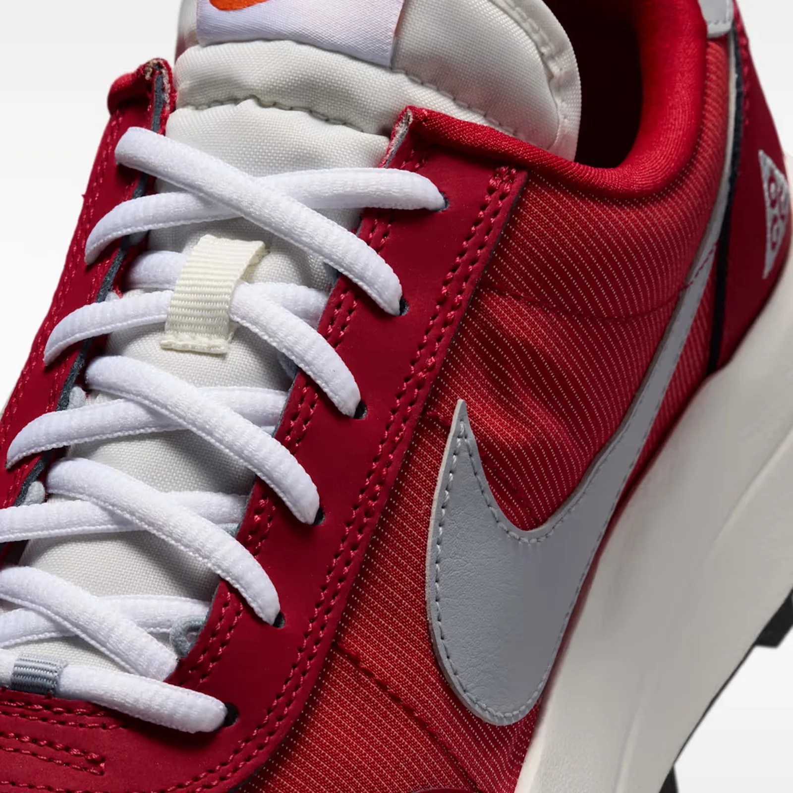 Close-up of a red and white Nike sneaker with white laces and a grey Nike swoosh.