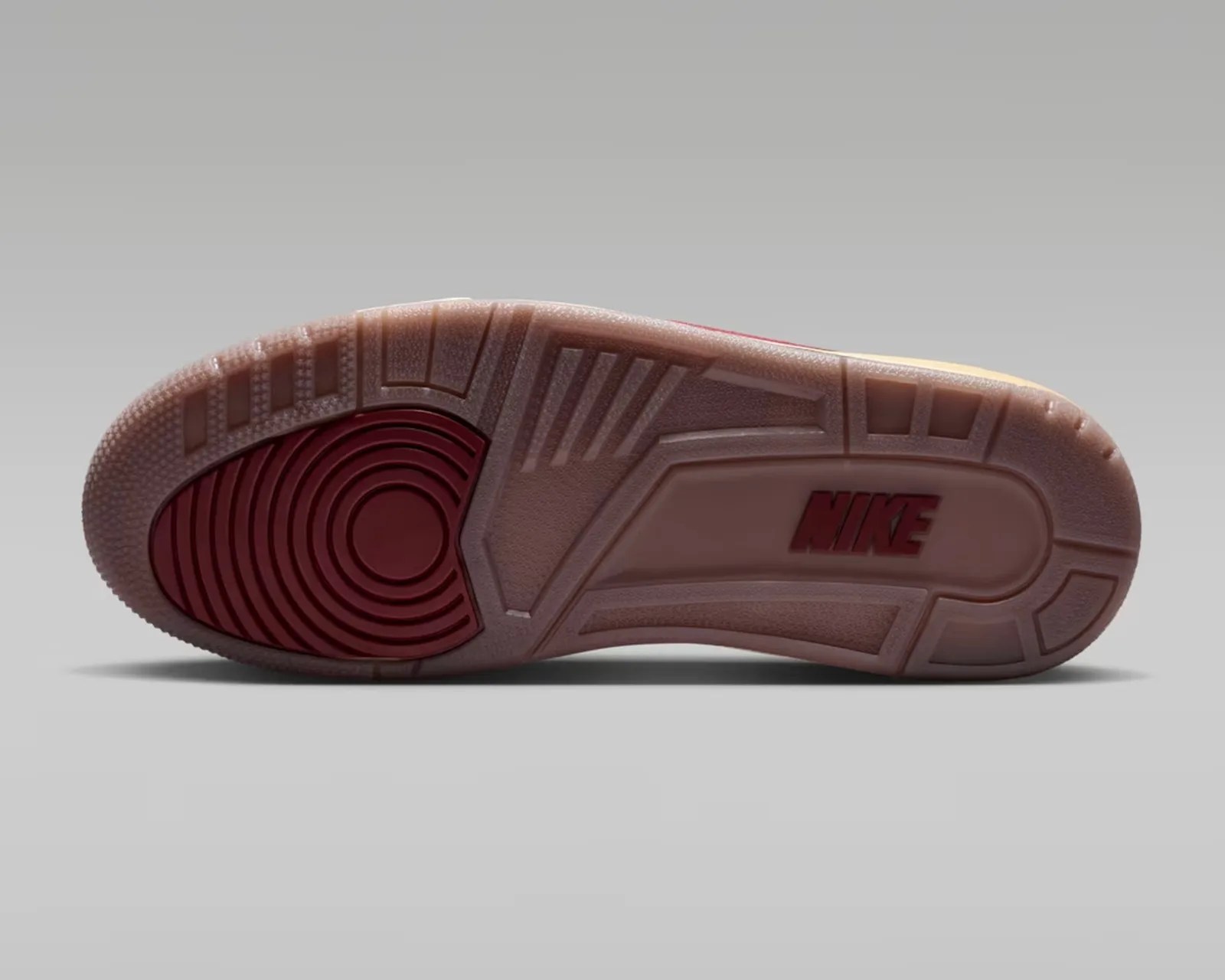 Sole of a Nike shoe with translucent rubber and red circular tread pattern on a gray background.