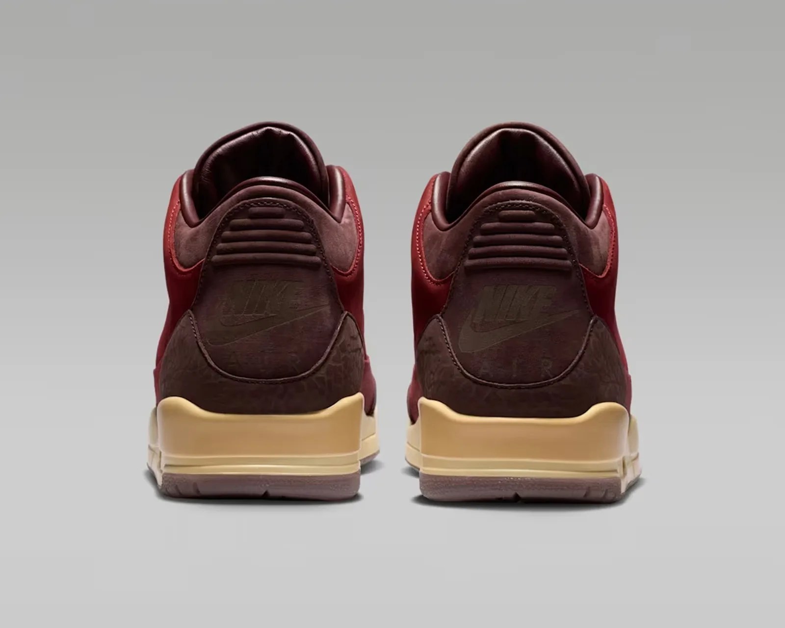 Pair of maroon and brown Nike Air sneakers shown from the back with cream-colored midsoles.