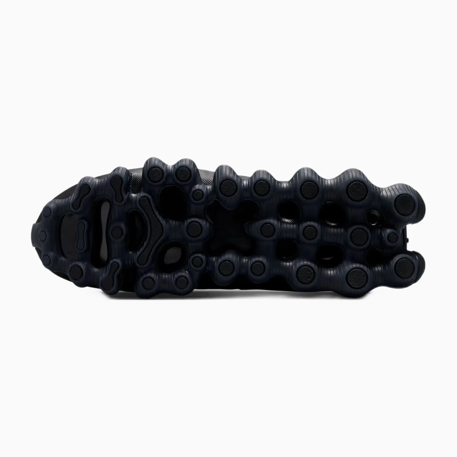Black textured rubber outsole with circular and oval traction pods on a shoe.