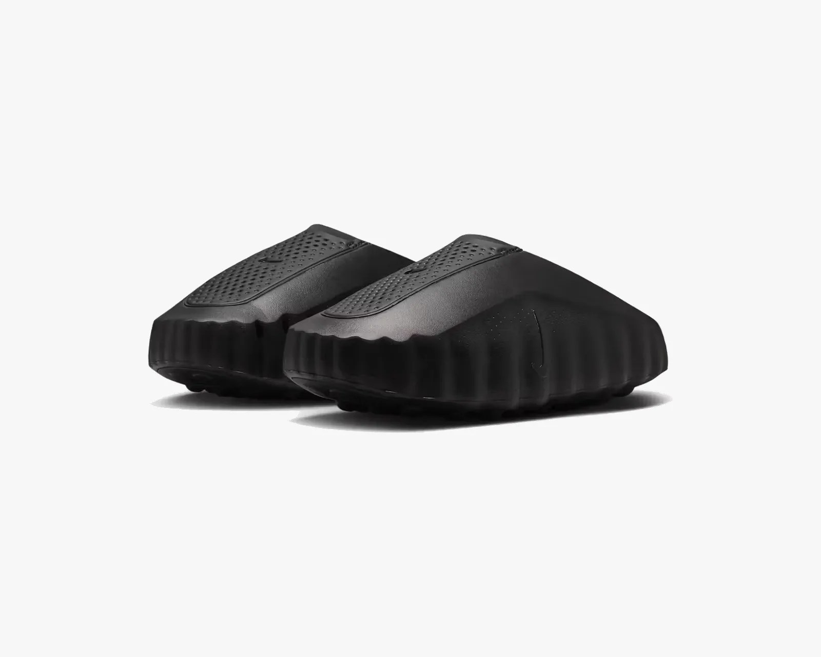 Pair of black slip-on slides with textured upper and thick ridged sole on a white background.