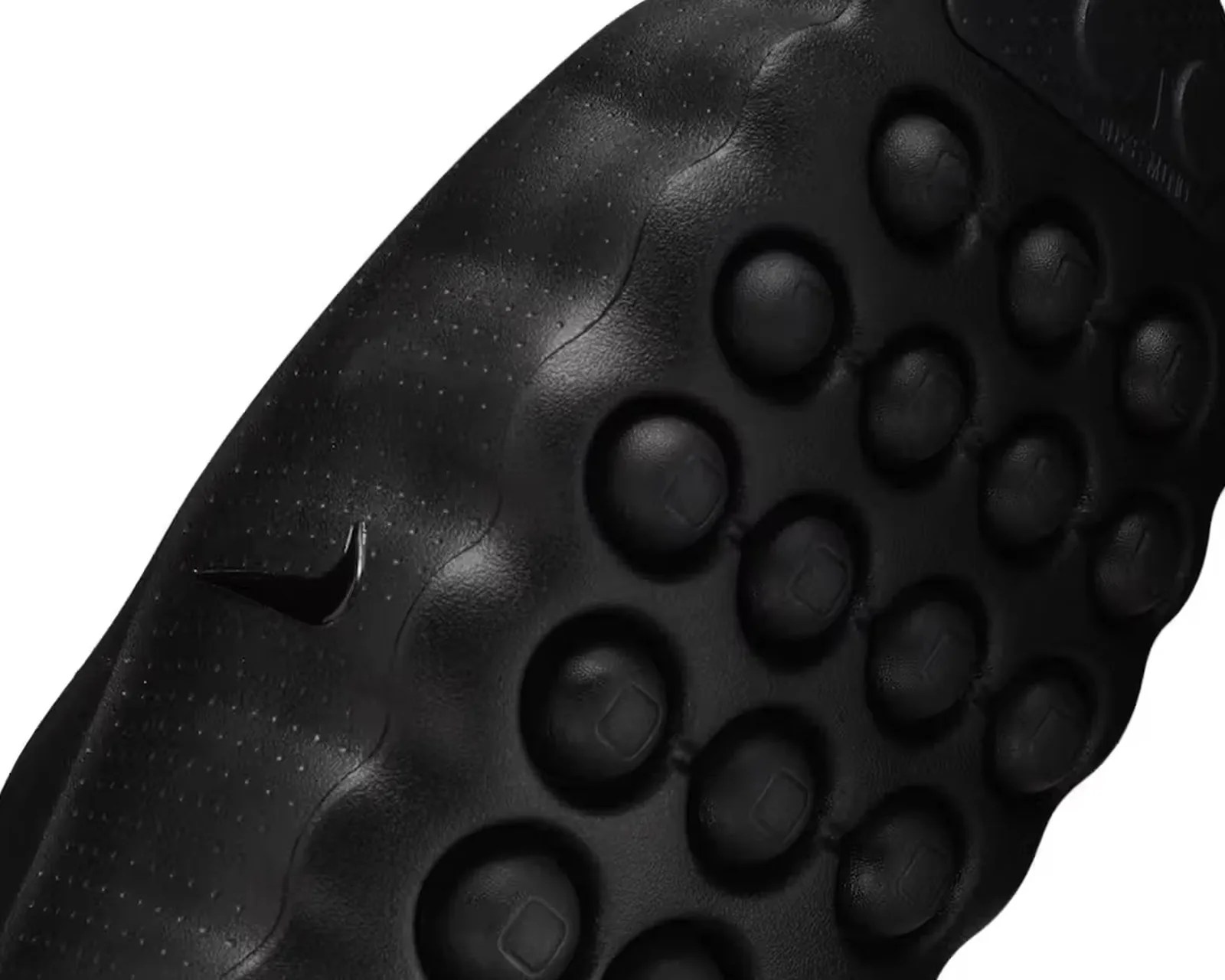 Close-up of the black textured sole of a Nike shoe featuring circular grip patterns and a small Nike swoosh logo.
