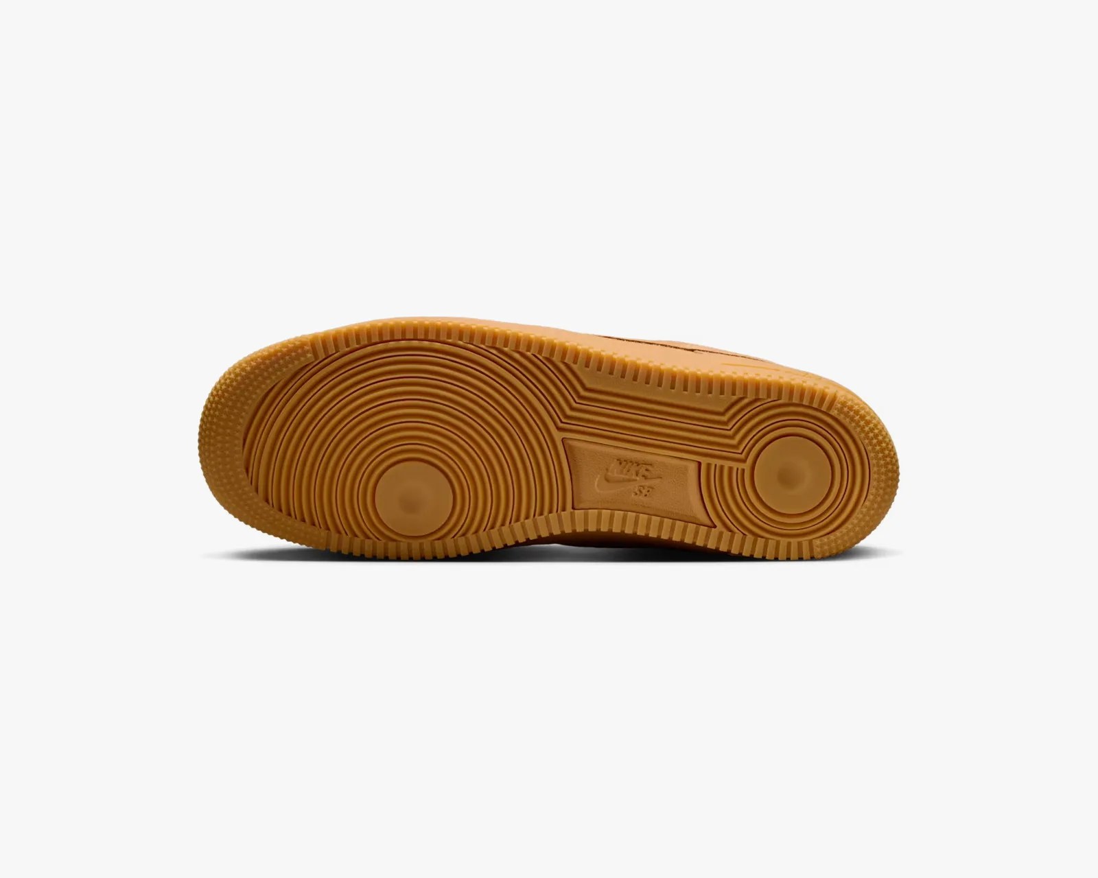 Gum rubber outsole of a Nike SB shoe with circular tread patterns and Nike SB logo.