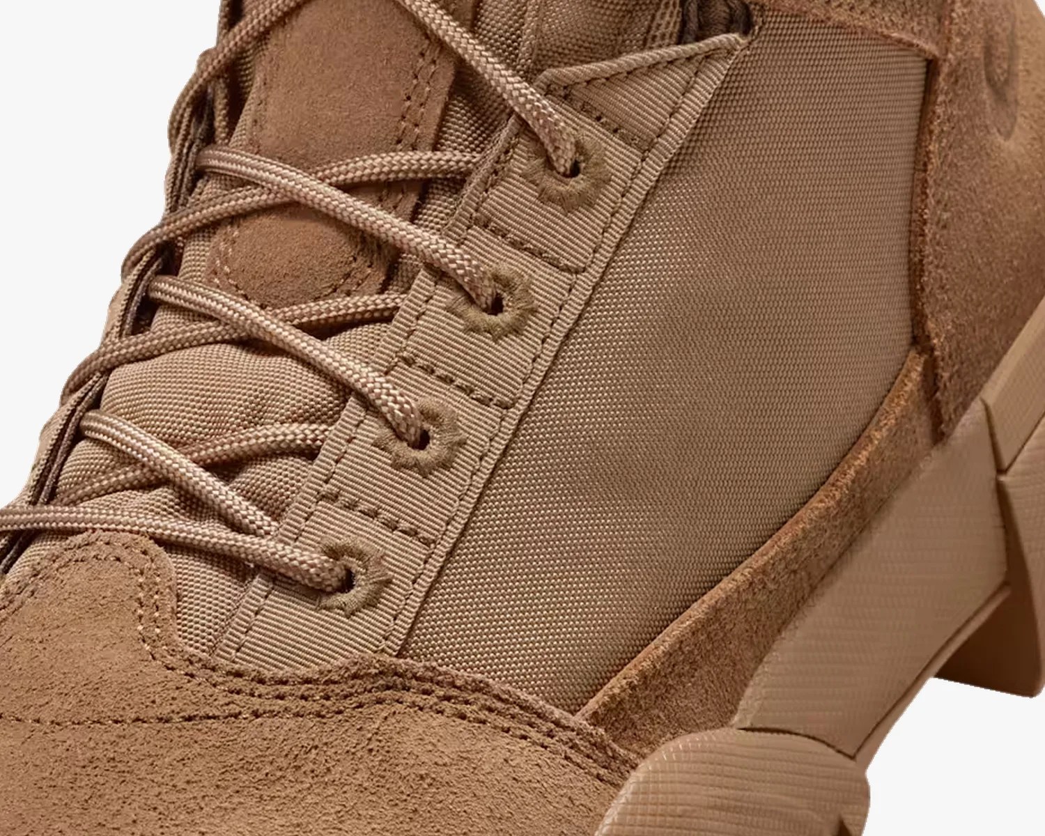 Close-up of a tan suede and fabric boot with matching tan laces and a textured sole.